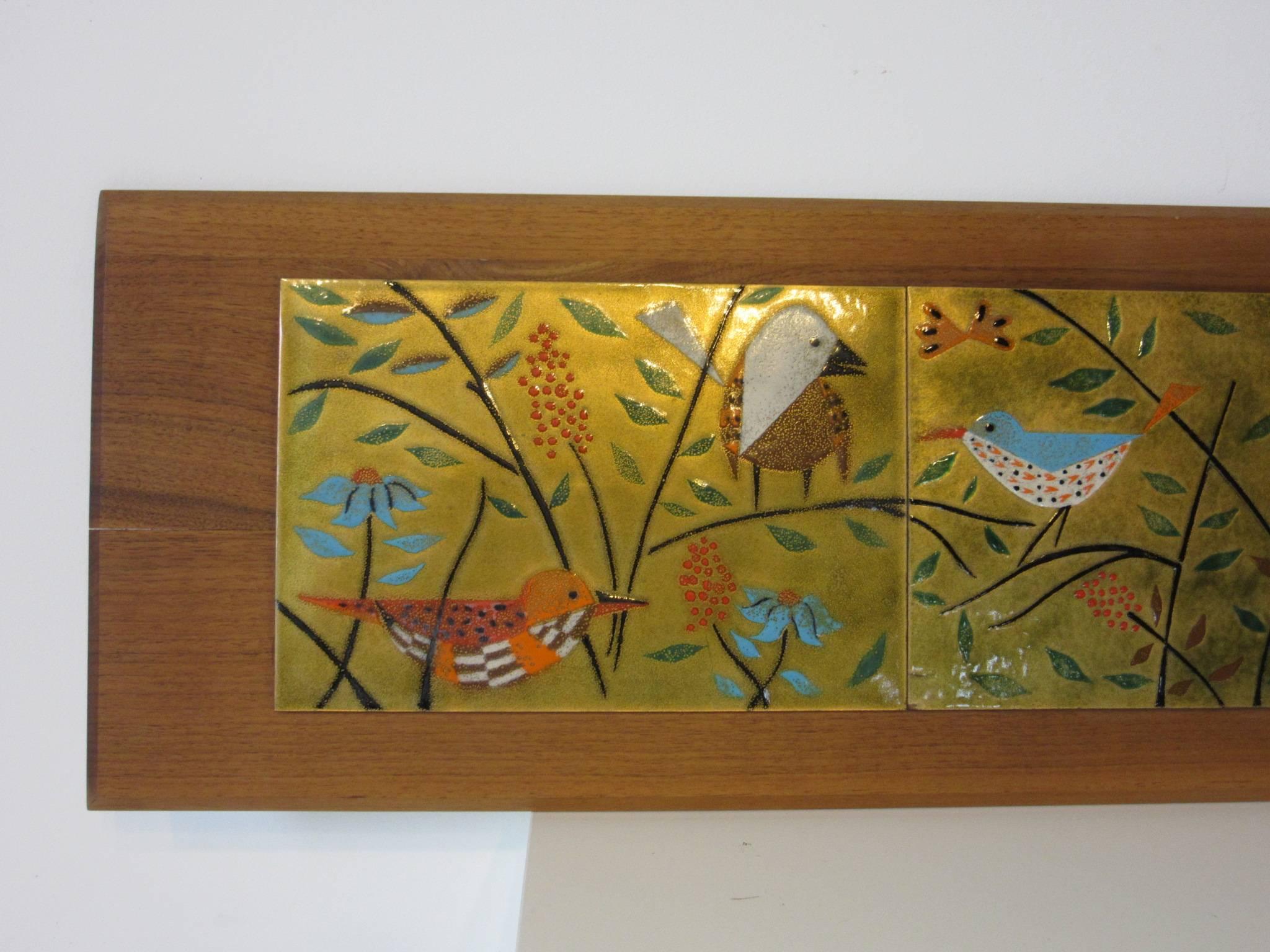A colorful copper enameled Danish panel depicting birds in their natural setting, mounted on a dark walnut wood backing with beveled edges and hangers to the verso.