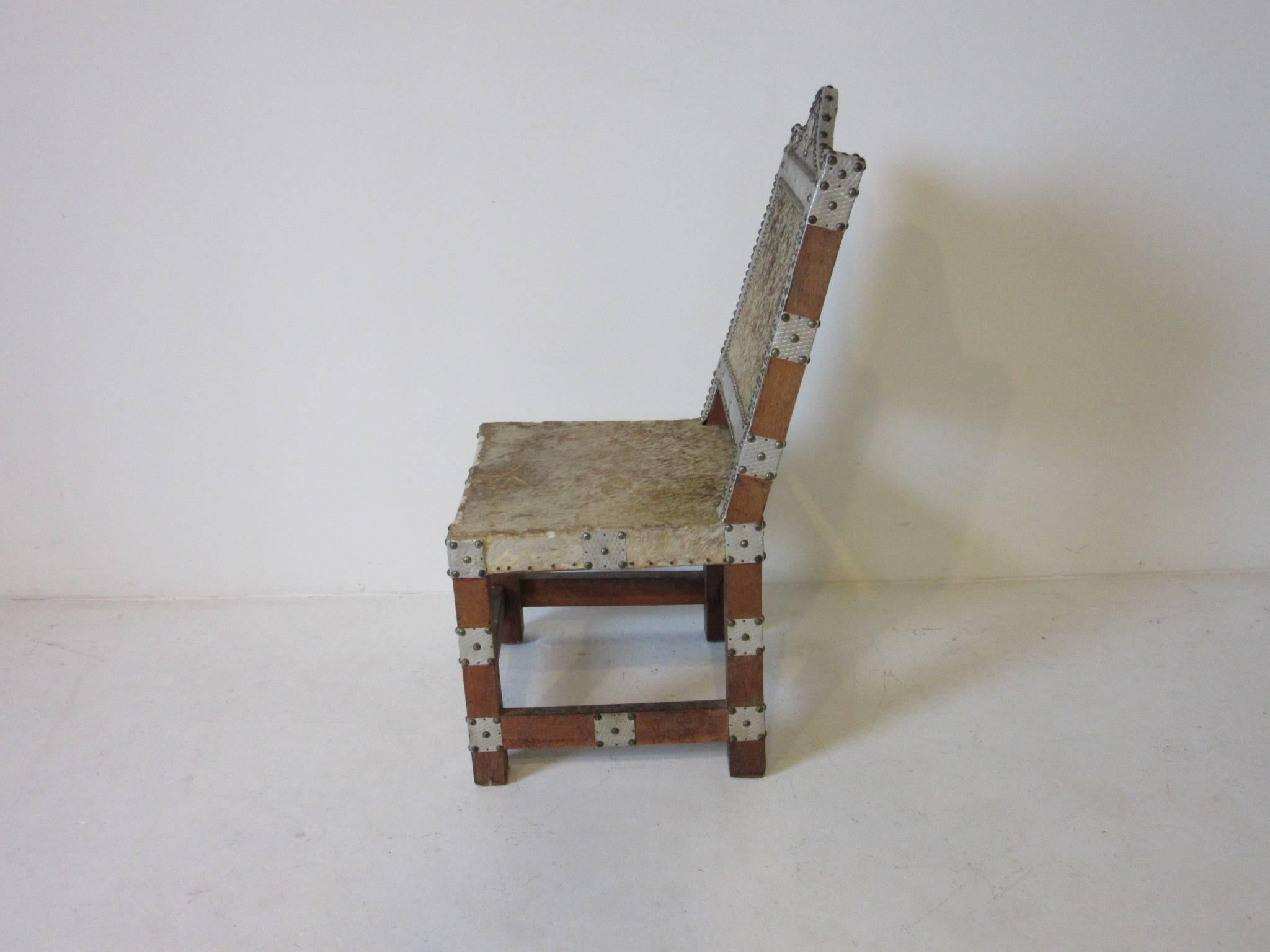 An African Royal or Prince chair with wood frame, animal skin seat and back embellished with nailed aluminum pieces and metal studs. In the style of the Asante or Ghana culture. 