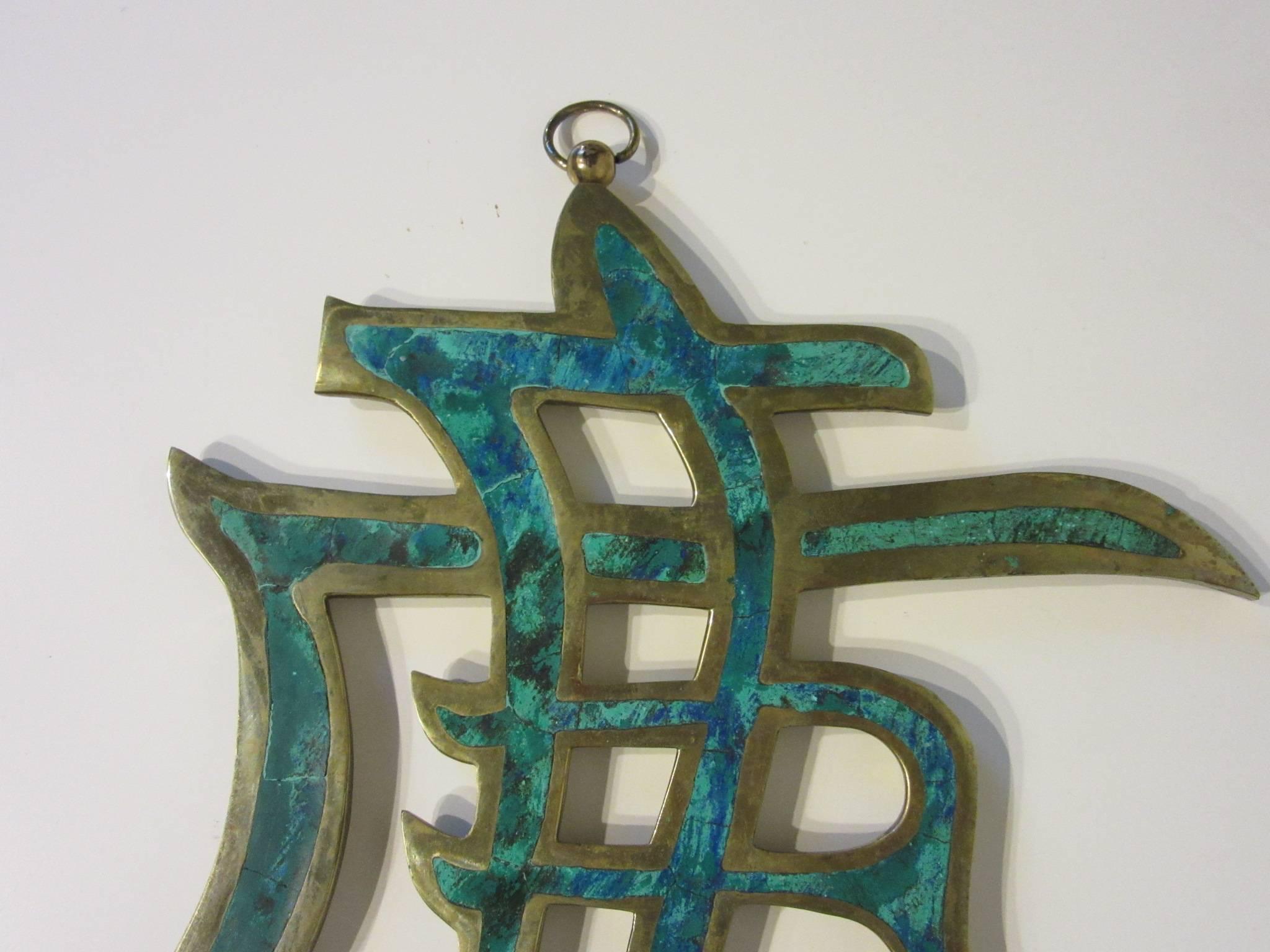 A brass and malachite handcrafted hanging wall ornament with inlay stone, hanger and retains the label 