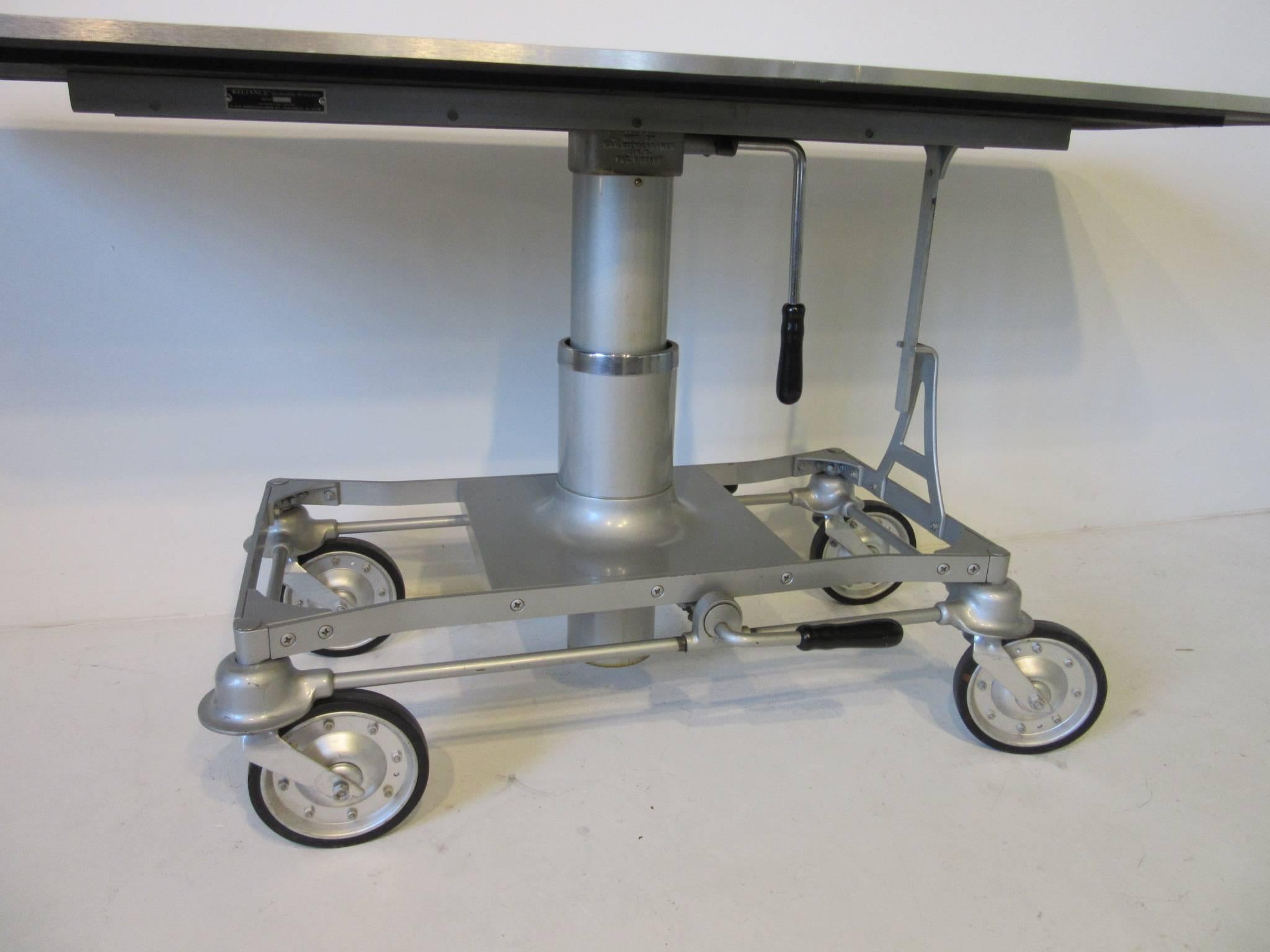 An Industrial machine age bar or serving table with large locking wheels, hydraulic pump lift unit for adjusting the height and replaced brushed stainless steel styled top. Great for the entertainment area, collector car garage or restaurant,