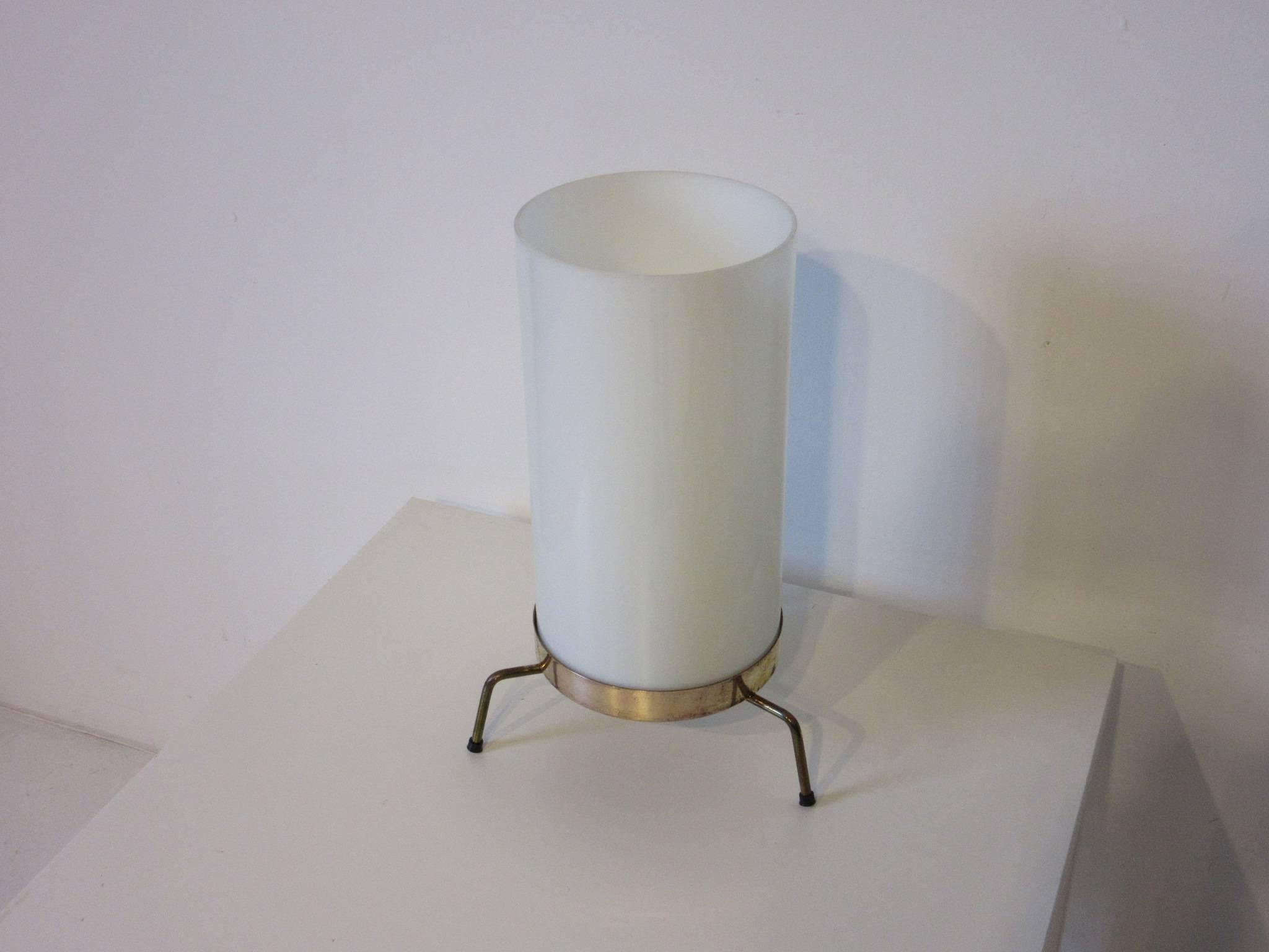A Paul McCobb table lamp with barrel styled white translucent glass shade sitting on a tri - legged brass base with bottom turn switch. Manufactured by the Northcraft Lamp & Accessories Company model # 2005.