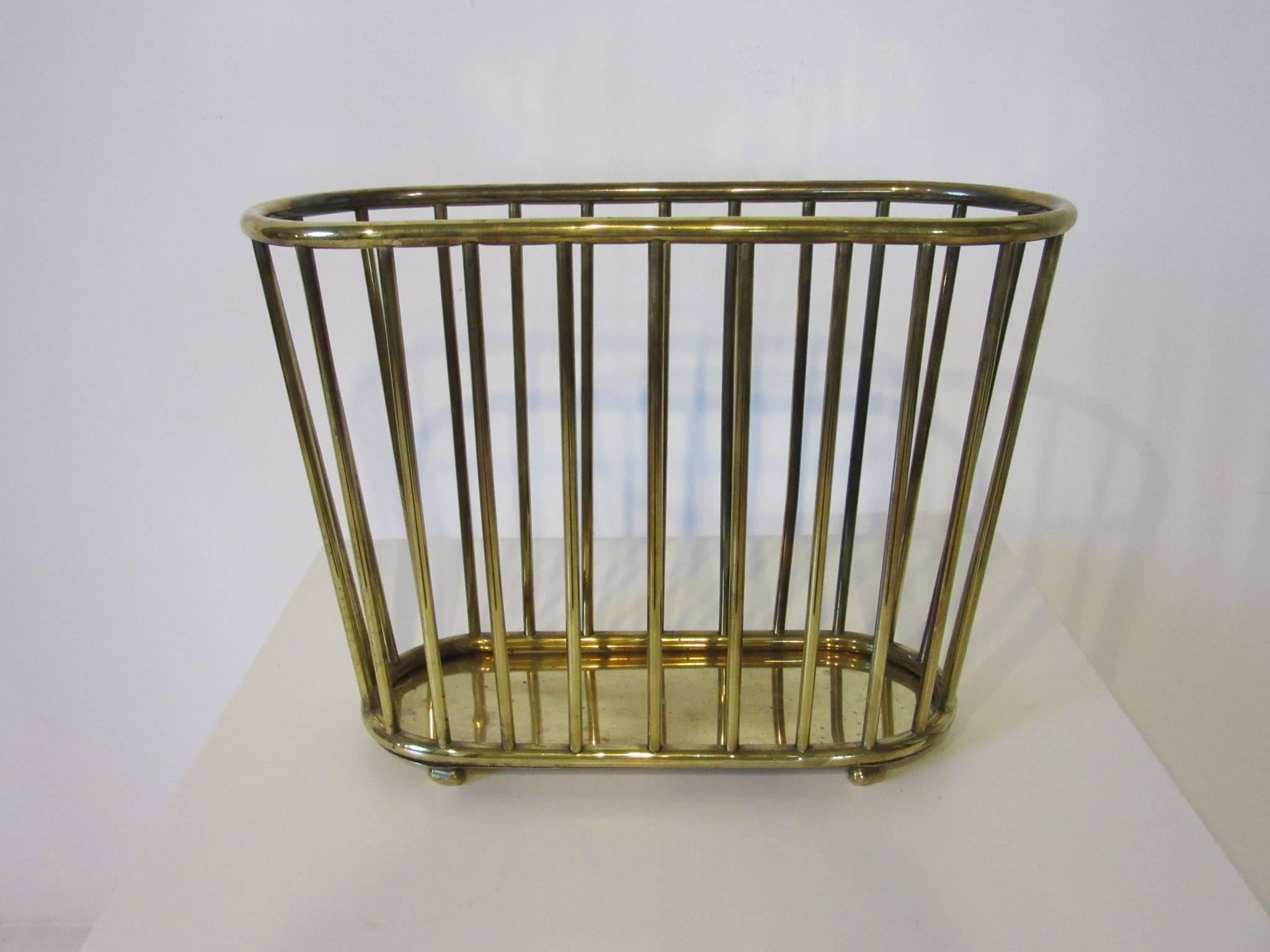 A brass magazine rack in the manner of Edward Wormley in a simple elegant style, marked to the inside bottom made by Gumps, San Francisco.