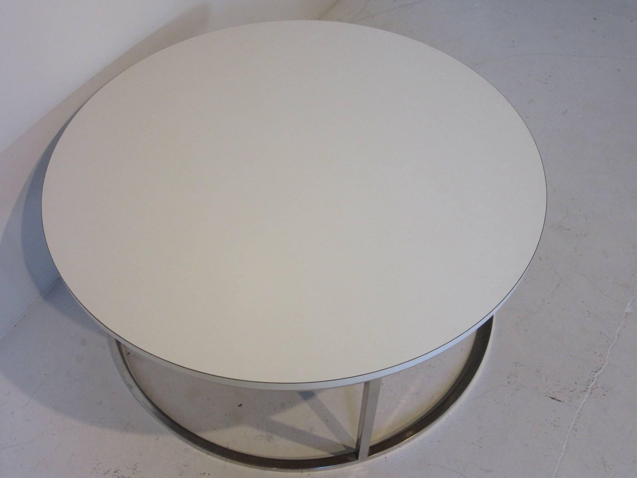 A chrome round coffee table with a white laminate top in the manner of Milo Baughman.