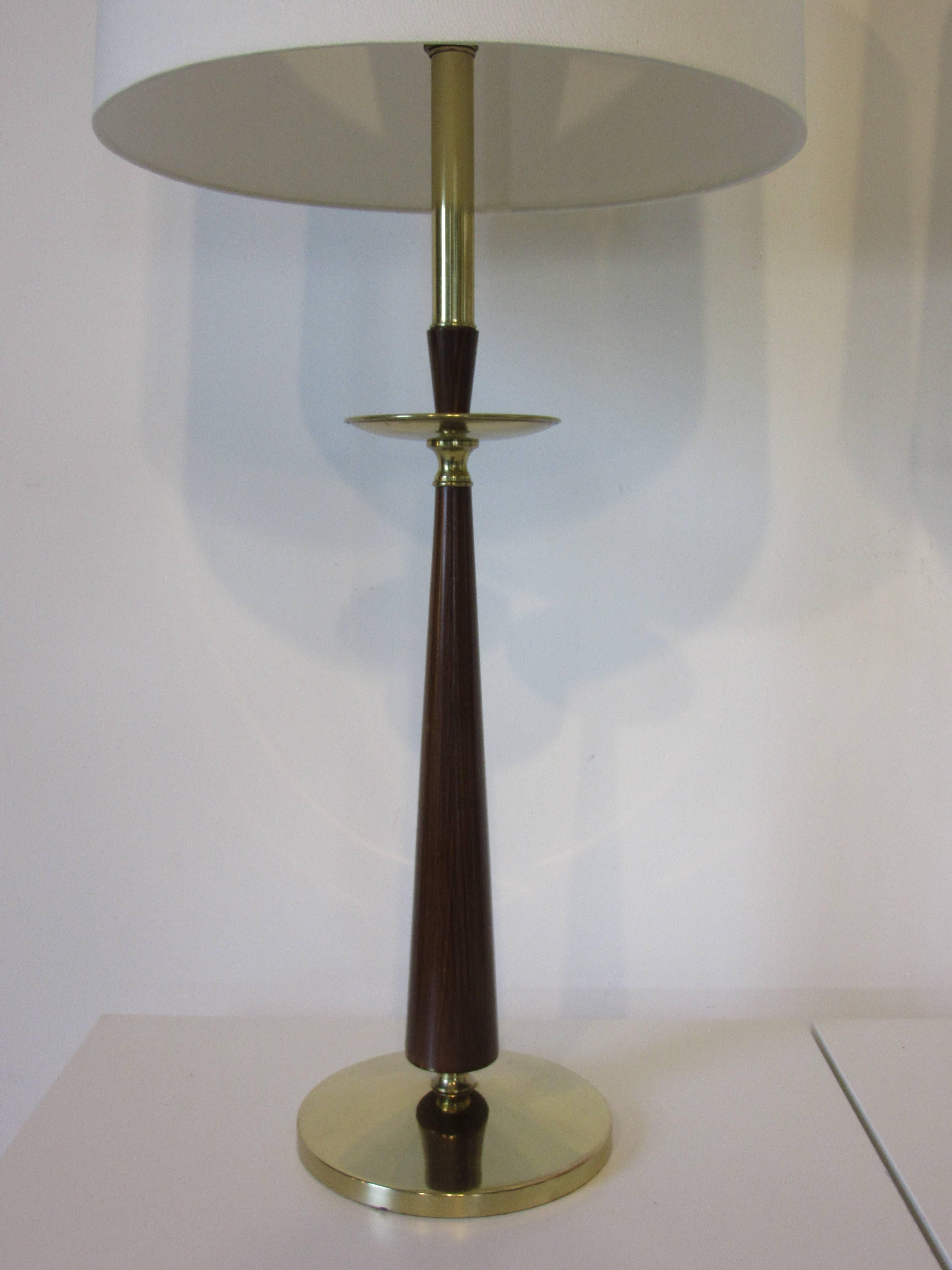 A pair of Mid-Century table lamps with brass bases and details with a faux rosewood body topped by cream colored linen shades in a simple and handsome design. Made by the Stiffel Lamp Company. The lampshade dia. is 15