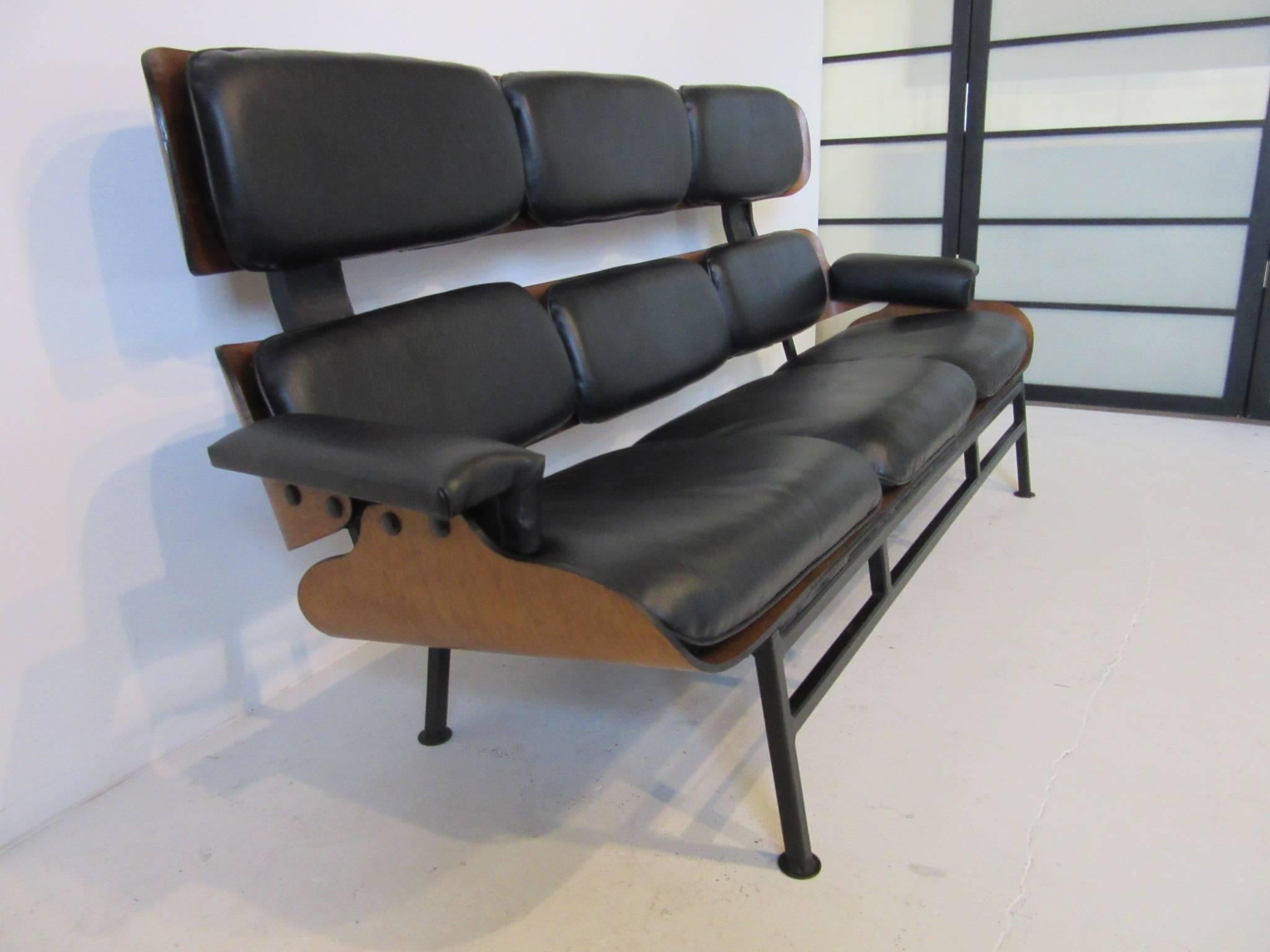 A rare Plycraft pre-production working prototype in the style of the lounge chairs, used in designing and researching the idea for a new type of sofa. Constructed of molded walnut wood with button attached leatherette cushions and a stain black