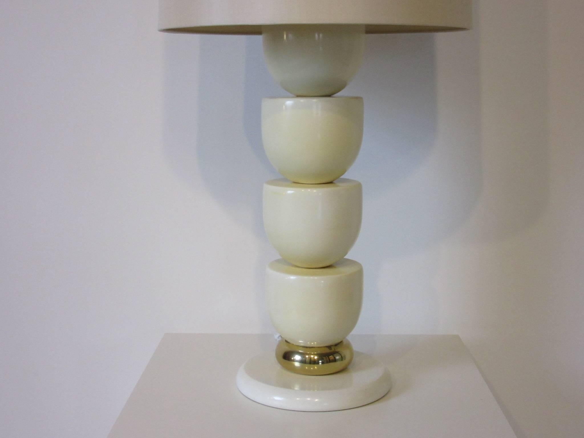 A very well crafted off-white colored lacquered solid wood sculptural table lamp with matching original finial and brass accent, topped with a parchment sand toned linen shade. A heavy and well constructed design in the manner of Steve Chase and