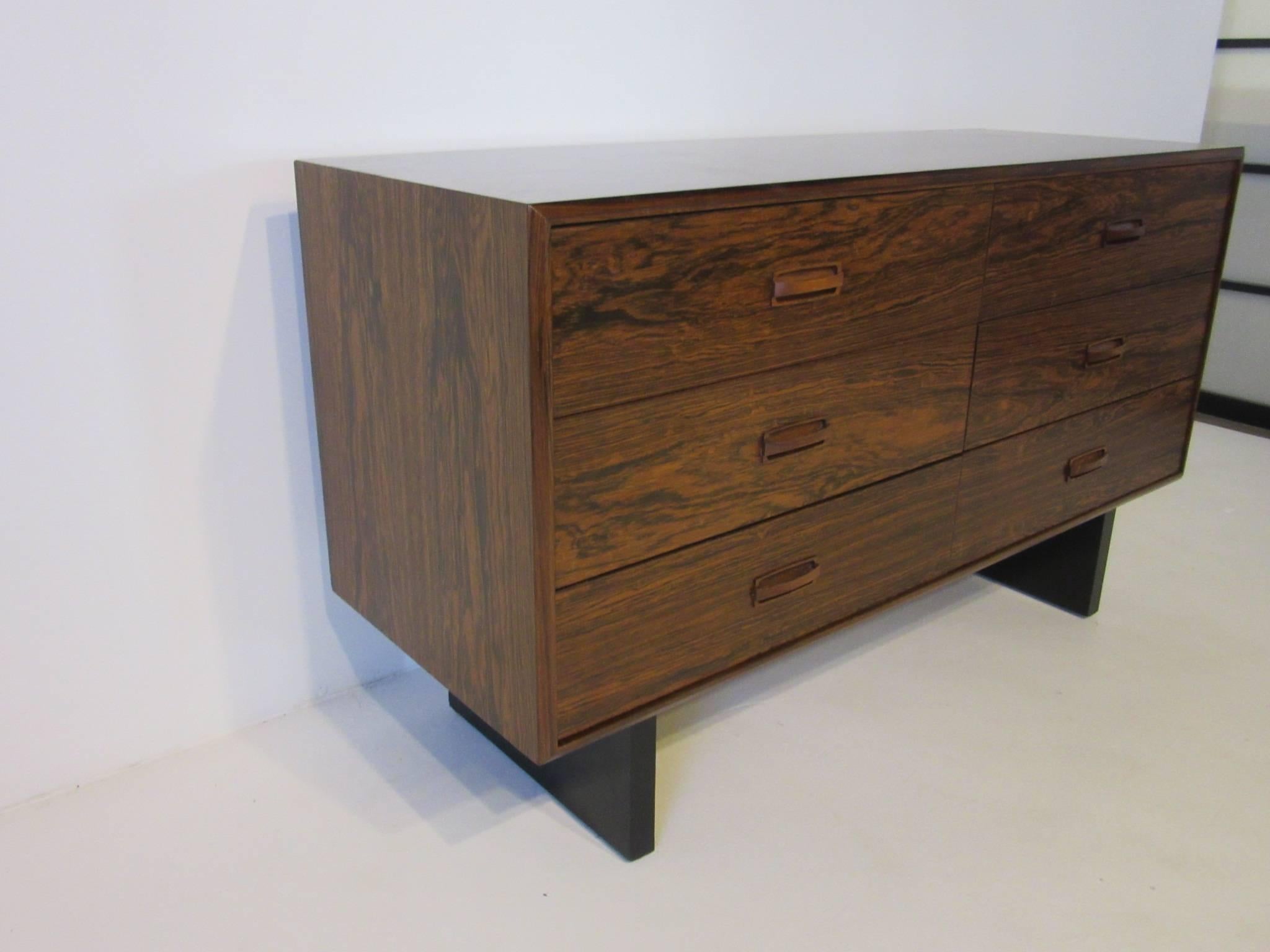 A well grained Brazilian rosewood six-drawer dresser chest with wooden pulls sitting on two satin black plinth styled bases made and designed in the manner of Danish modern. This compact sized piece works great for a smaller or tight fitting area.