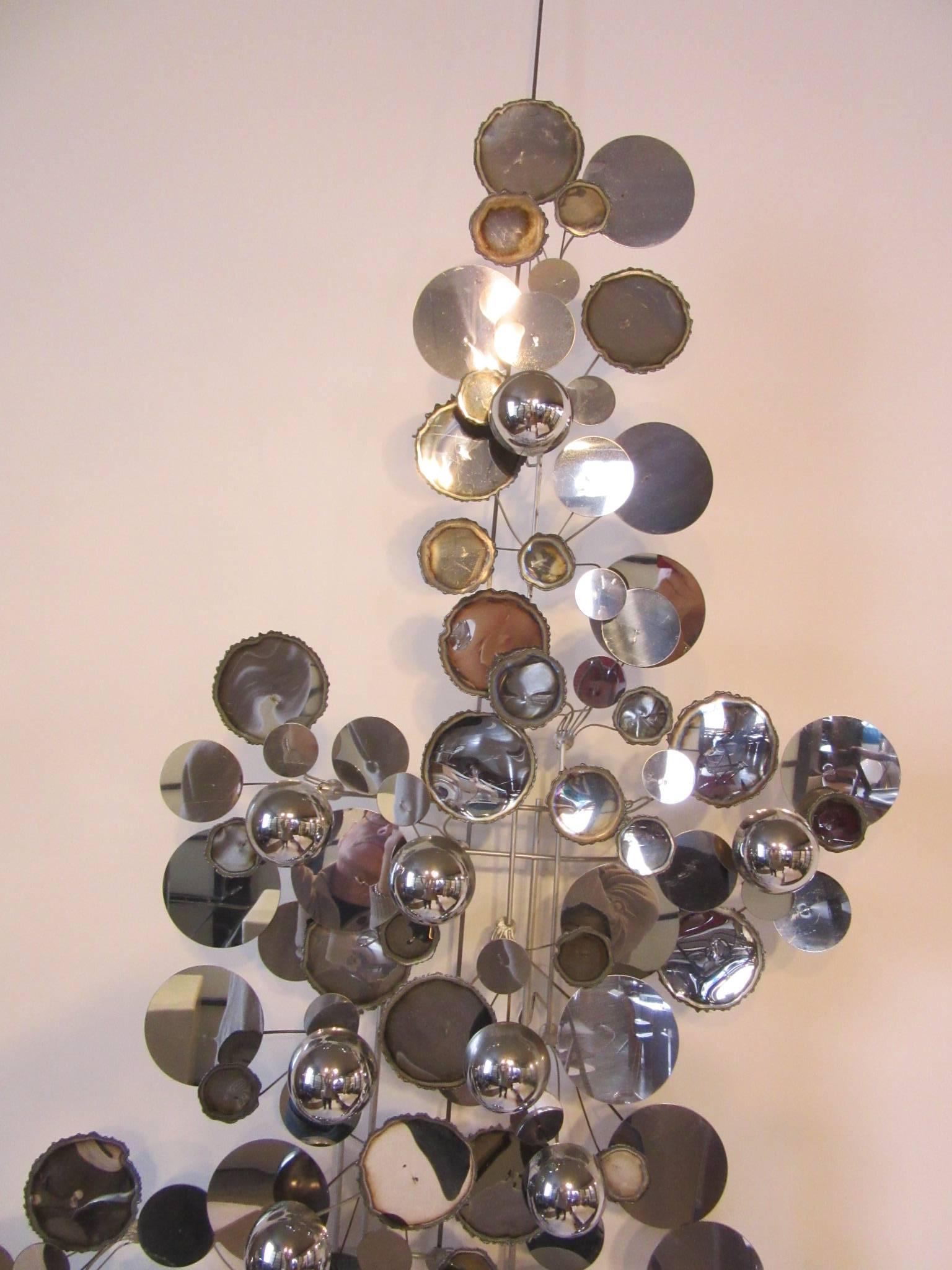 A chromed wall sculpture with torch cut and brazed edge circles, chrome circles and domed rain drop like pieces intermingled for a unique and interesting look, one of their best and most sought after designs. It can be hung vertically or