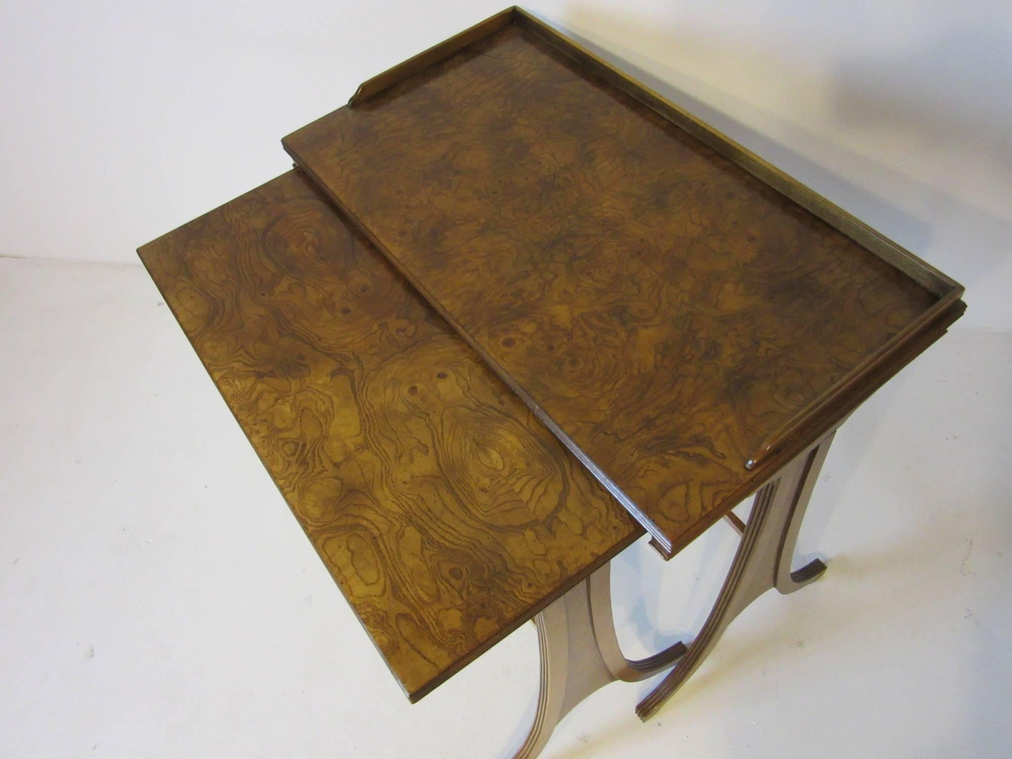 A set of two nesting burl wood side tables with formal Regency styled legs and details but with a modern twist. Crafted by the Baker Furniture company and still retaining the metal manufactures tag to the bottom. The inner table measurements are