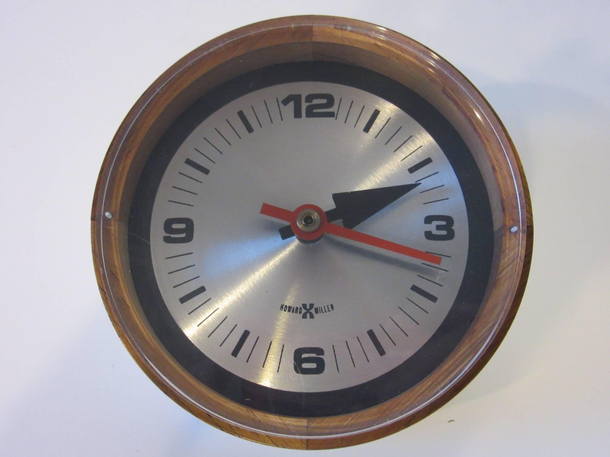 A rosewood and brushed aluminium table clock with angled base for viewing, a Lucite face plate protects the hands manufactured by the Howard Miller Clock Company model # 663 with the original working battery operated motor and labels.