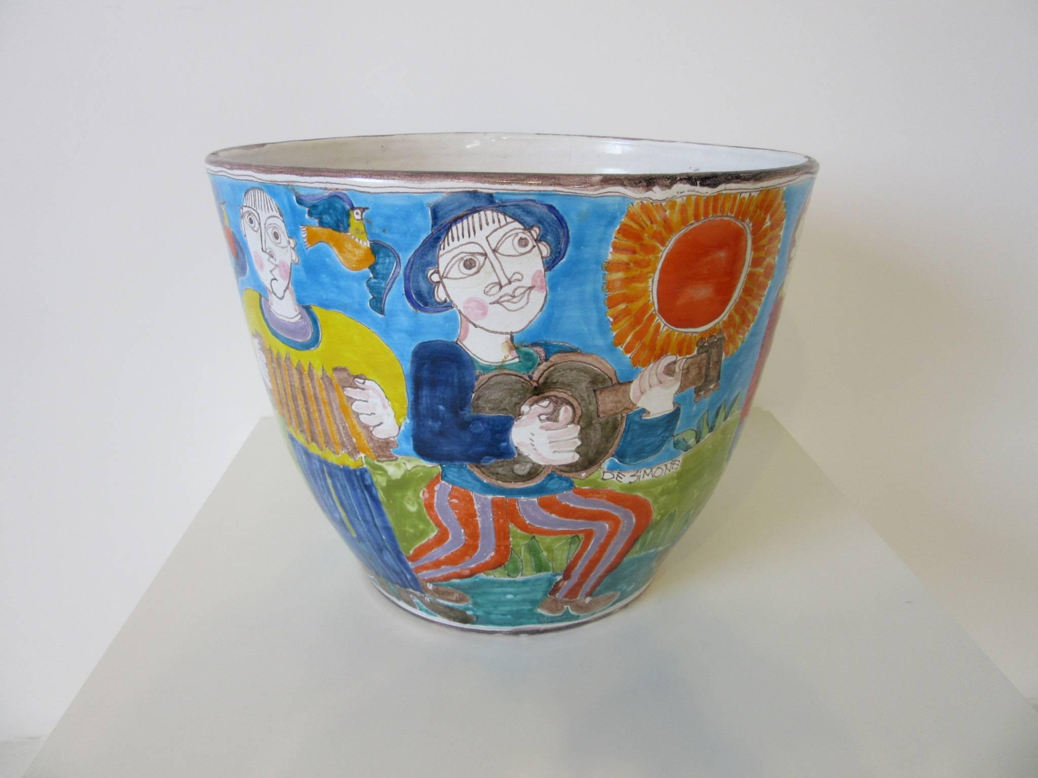 A whimsical hand-painted pot or planter with a festive musical scene with dancing and partying depicted around the entire surface. A rare very large form by this artist signed in the scene and to the bottom by DeSimone, made in Italy.