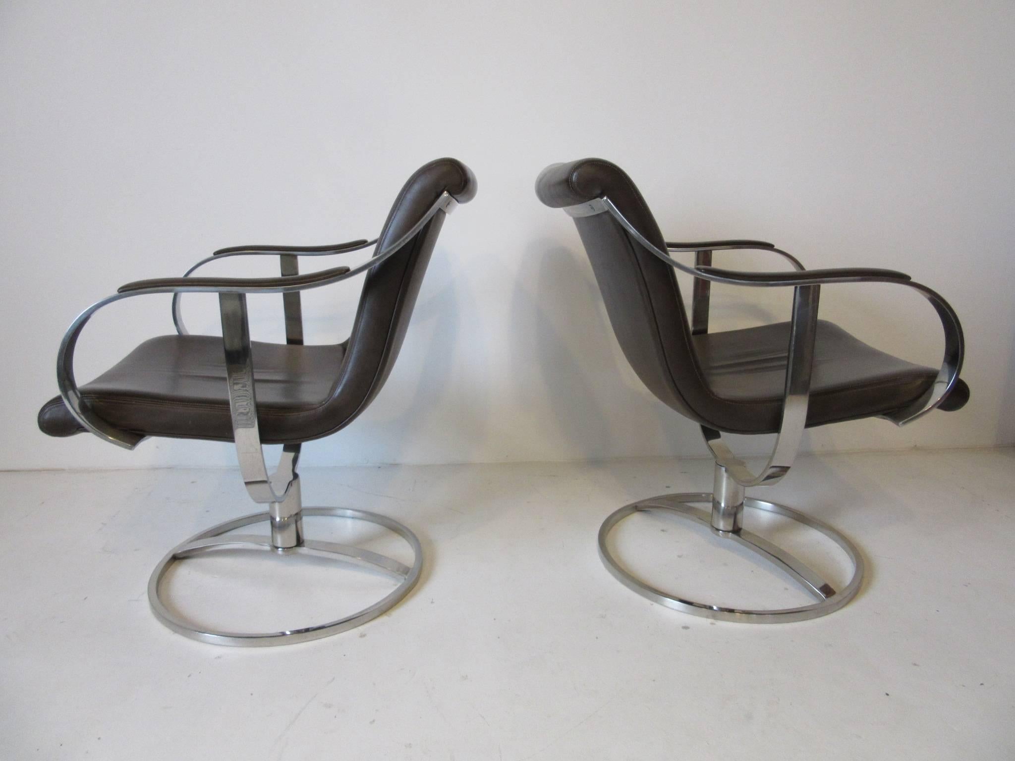 A pair of well constructed chromed steel sculptural lounge chairs with dark coffee bean colored leather upholstery and swivelling bases . Manufactured by the Steelcase Furniture company.
