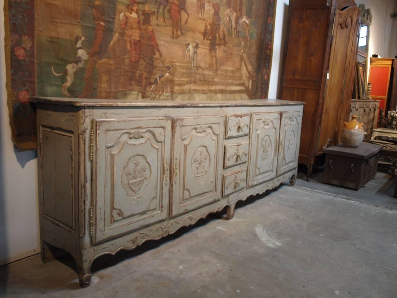 A very charming and very long later 19th century French Provençal enfilade buffet in painted wood. Four molded door panels and three drawers, all with wonderful carving detail. This terrific serving piece offers great storage.