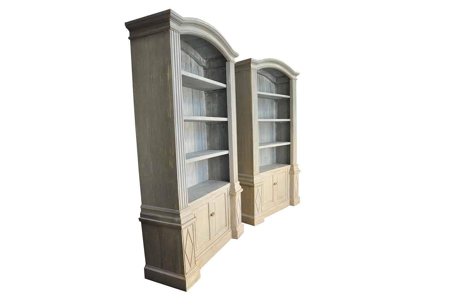 An outstanding pair of bookcases constructed from 18th century Spanish boisserie elements.  Beautifully constructed with open shelving and double doors that open to reveal a single shelf.  The painted finish is in tones of soft grey.