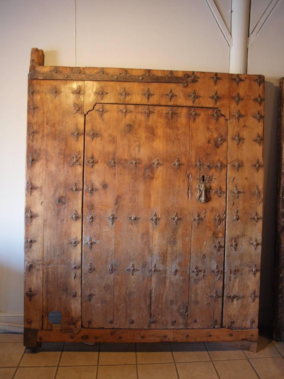 Exceptional and monumental 17th century Spanish entry door. Wonderfully constructed from Meleze wood - a very hard pine. Outstanding iron ornamentation with massive hinges, a spectacular knocker and flower-like studs. To the backside, the inner door