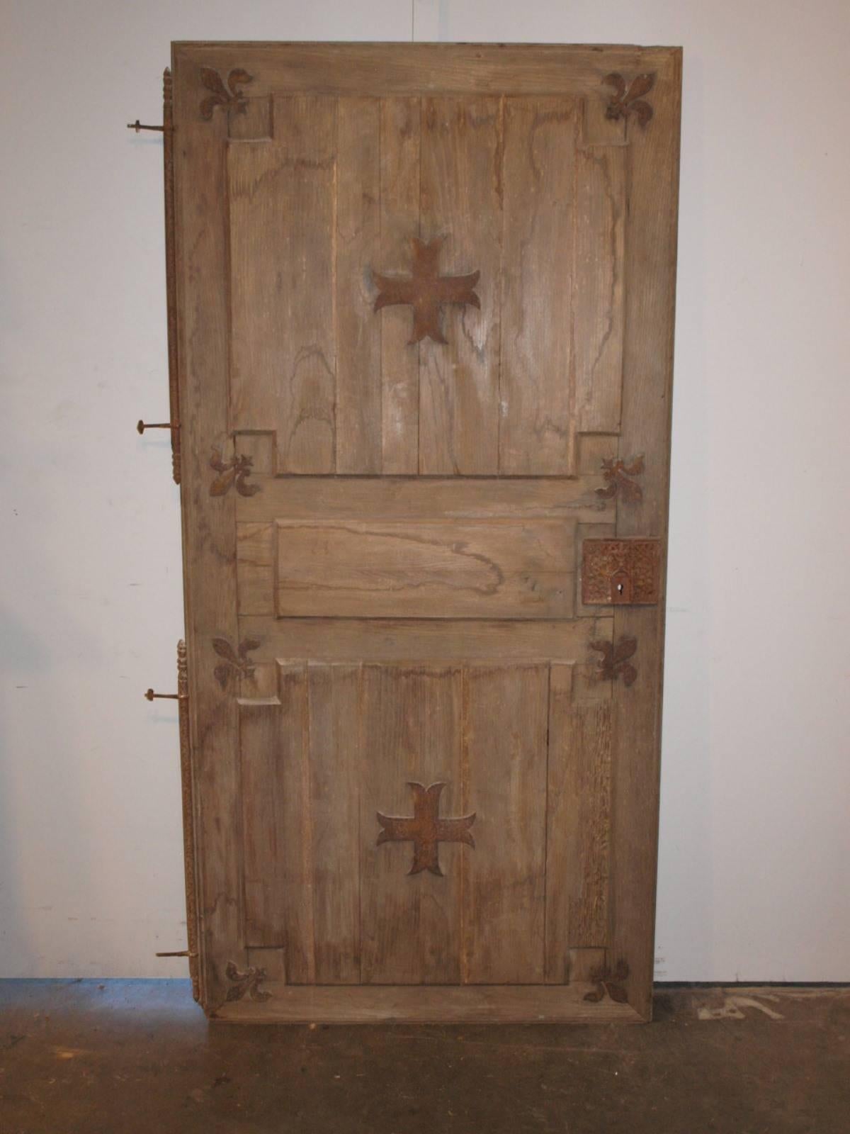 A charming pair of earlier 19th century armoire doors from the Sologne region in France.  Beautifully constructed from oak and adorned with iron Fleur De Lys and crosses.  The lock cover of one door has a fantastic iron plaque.  The pair of doors