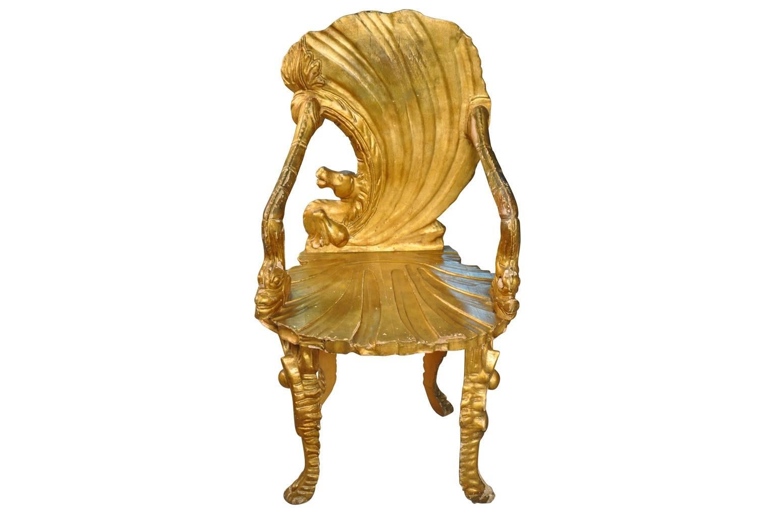 A stunning 19th century Venetian Grotto armchair in giltwood. Hand-carved with the seat and back in the form of an open scallop shell. The armrests are in the form of dolphins and supported by conch shell legs. A very striking decorative piece