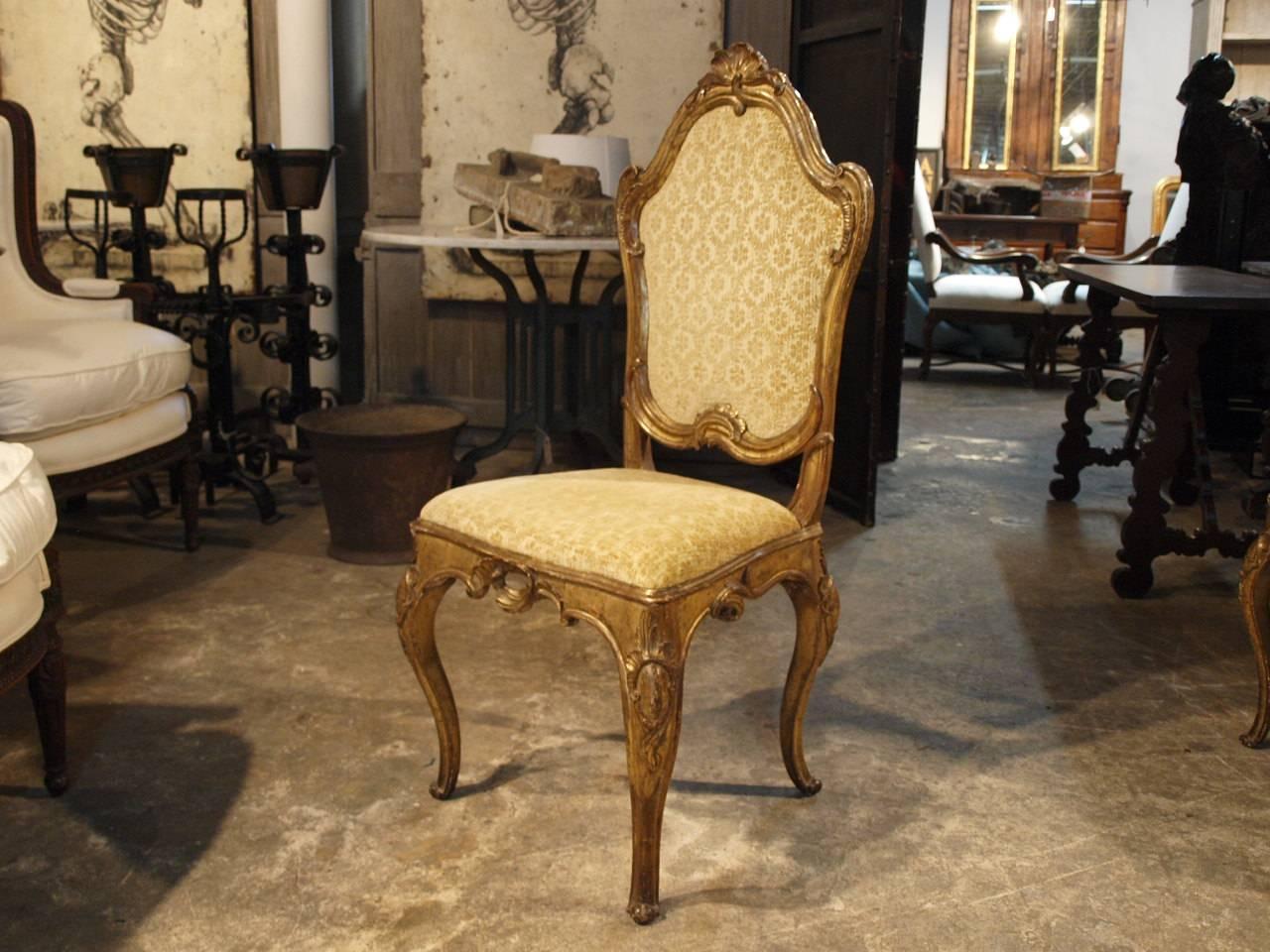 An outstanding set of six Venetian Rococo side dining chairs in silvered and gold gilt wood. Each with an arched shaped crestrail surmounted by a rocaille cresting over a cartouche shaped padded back, raised on cabriole legs with knees carved with