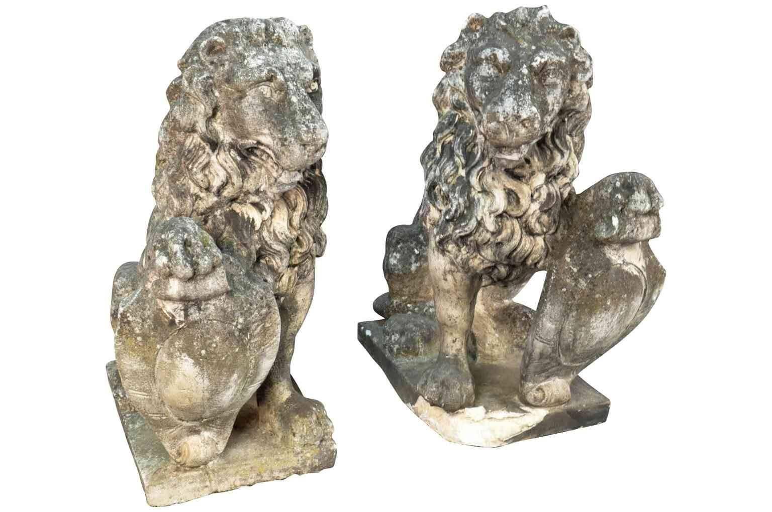 A stunning pair of 19th century lions carved from stone. Beautiful detail of head and mane, seated on plinths holding shields. Gorgeous patina. Wonderful at any entryway or as interior decoration.
