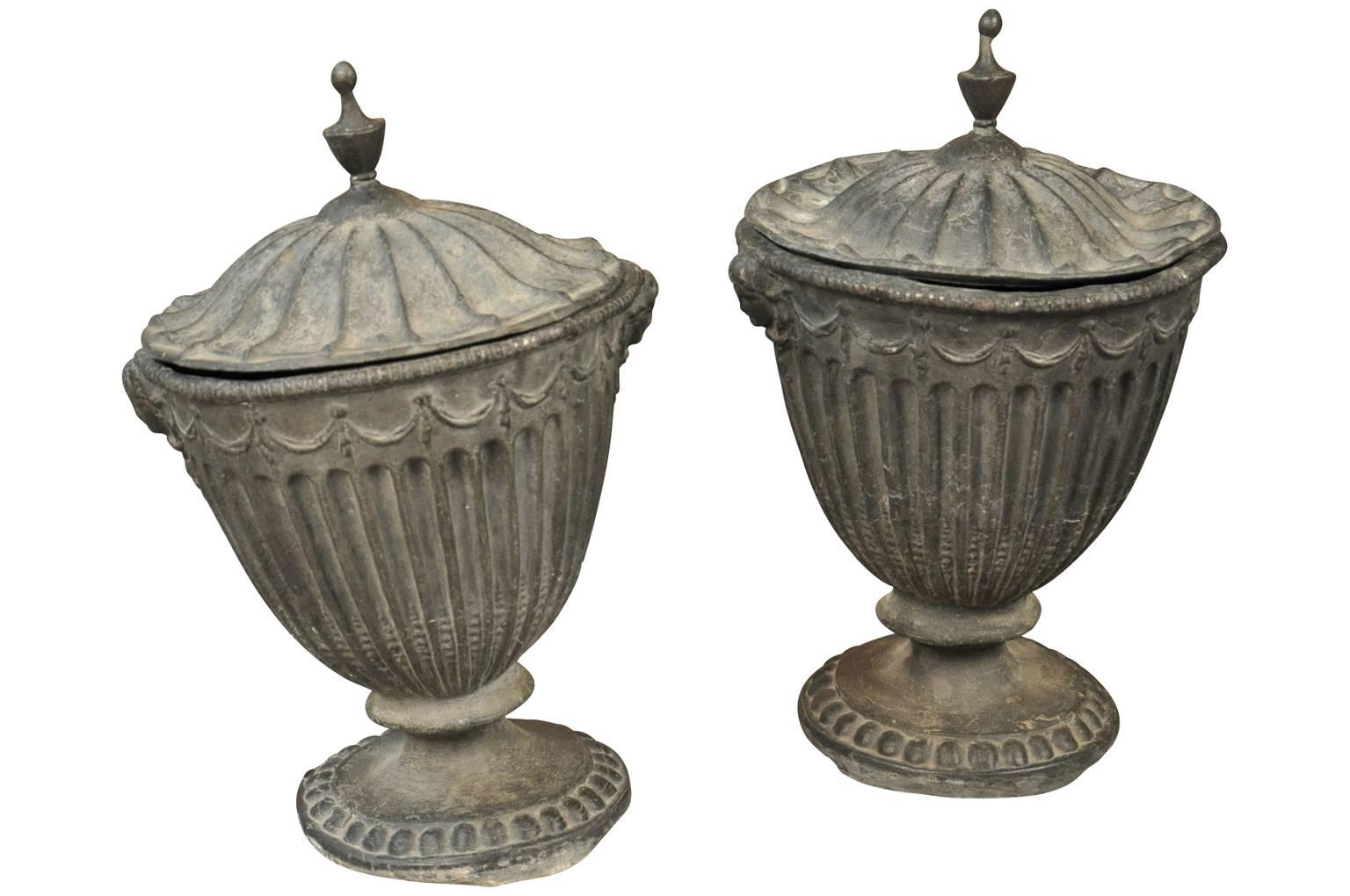 A stunning pair of 18th century English lidded urns handsomely crafted from lead. Exquisite mantel or tabletop decoration. Wonderful as garden accents as well.