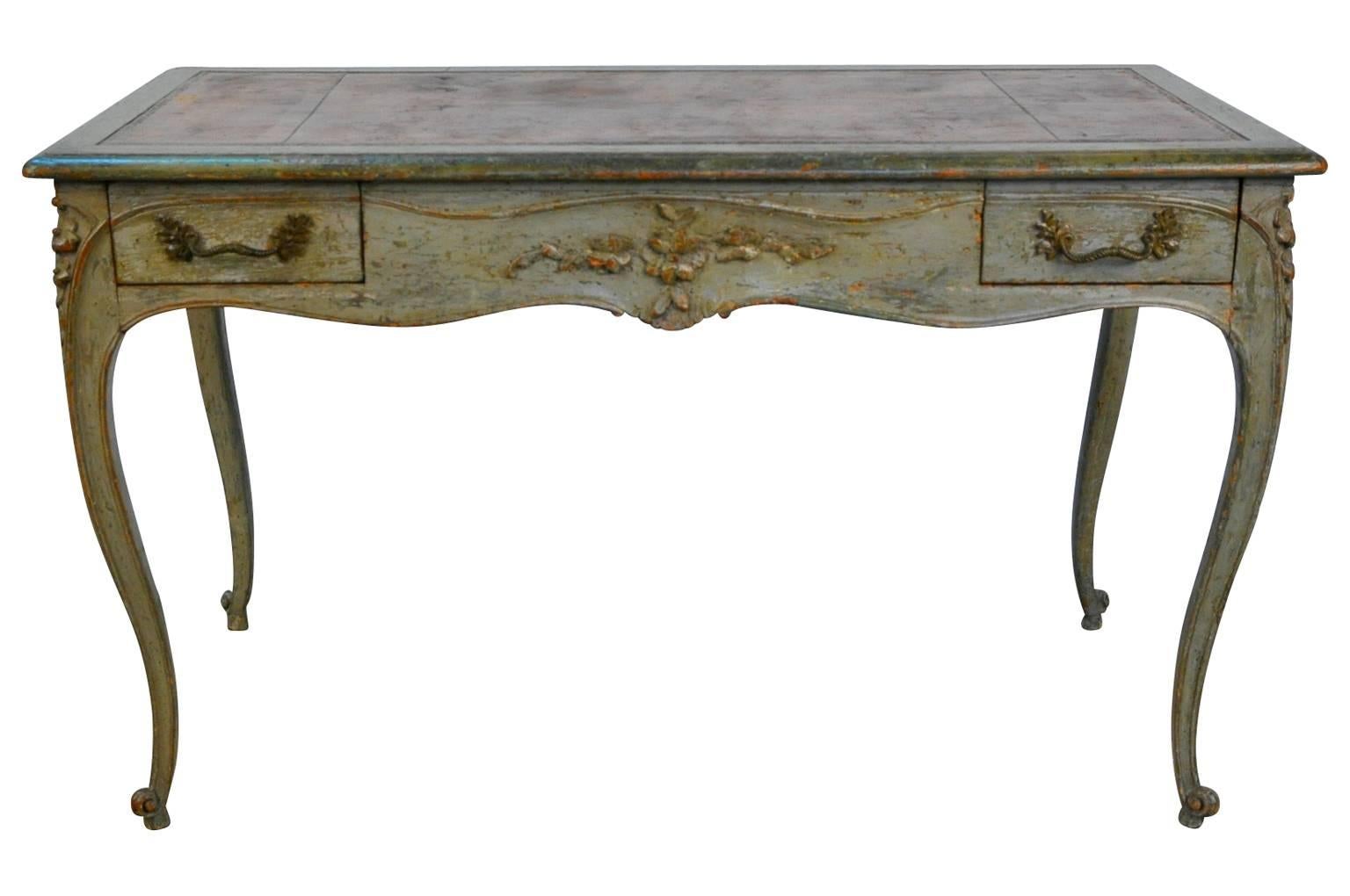 A sensational French Louis XV period desk in painted wood and leather top. Tremendous painted finish and patina. Soundly constructed with two drawers and delightful carved floral motifs to all sides. A fabulous pieces for any living area or bedroom.