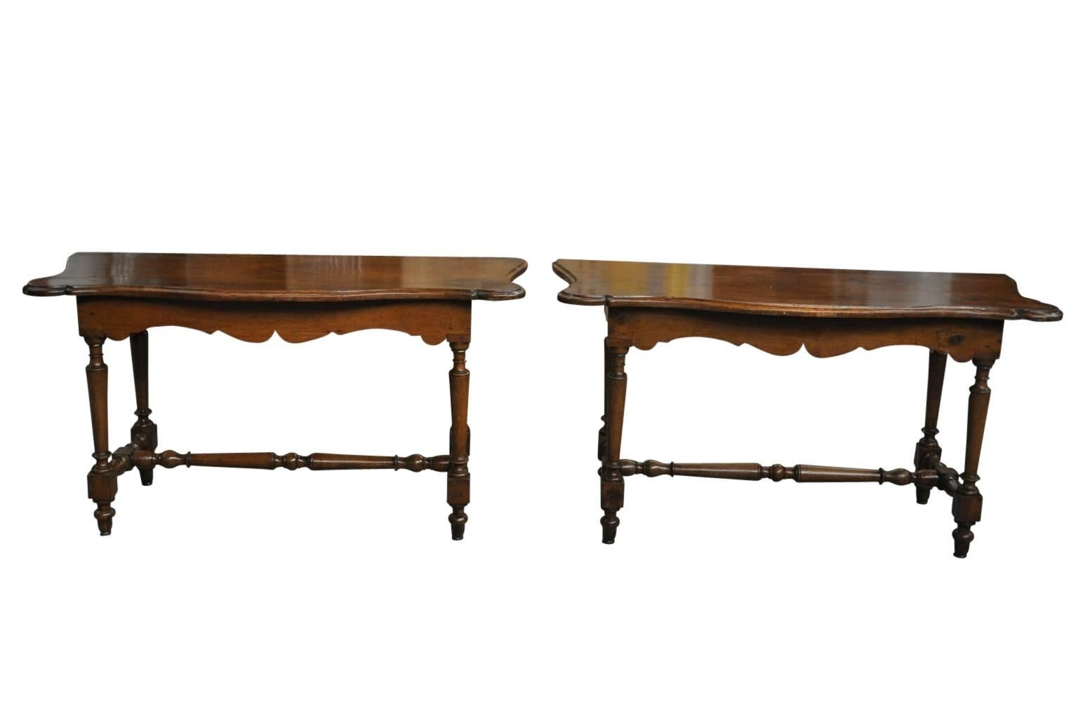 An outstanding and stunning pair of 18th century Italian console tables from Tuscany. Expertly crafted from walnut with a shaped top surface with beautiful edge finish, sculpted aprons and turned legs and stretchers. The patina is very rich and