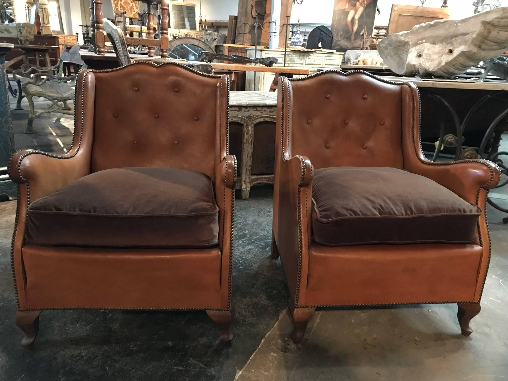 A terrific pair of French Art Deco leather club chairs. Soundly constructed and very comfortable with great nailhead detailing. The cushions have been newly reupholstered in velvet. Wonderful accent chairs for any living room, library or office.