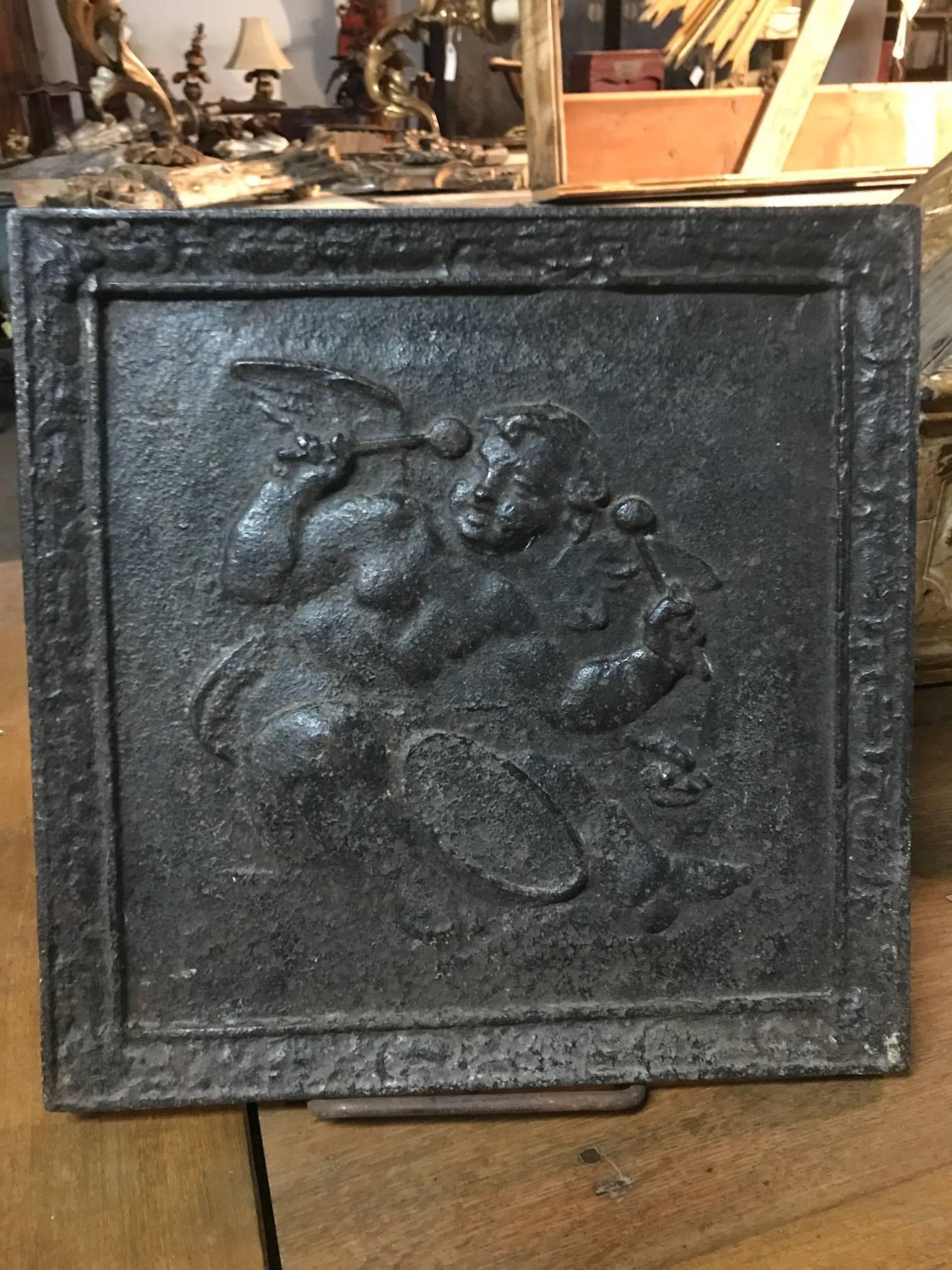 A very charming diminutive cast iron fireback from France. A wonderful motif of a cherub or putti playing the drum.