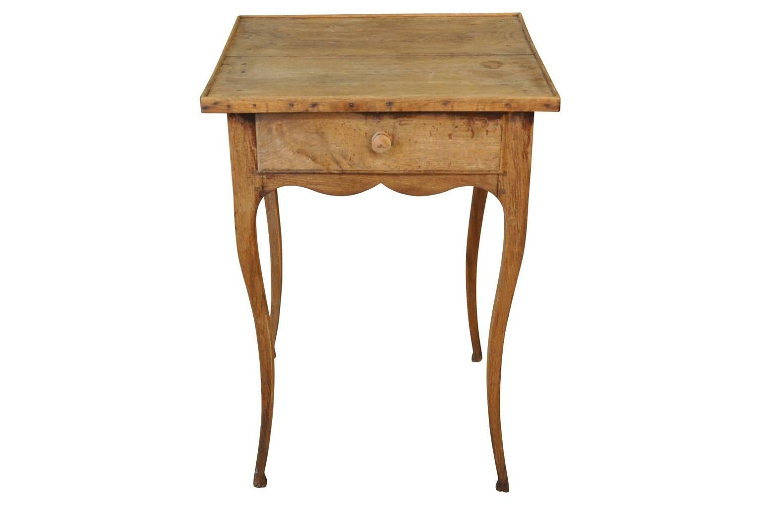 A very charming early 19th century Country French side table in washed or bleached oak.  Beautifully constructed with a single drawer, sculpted apron and gentle cabriole legs.  