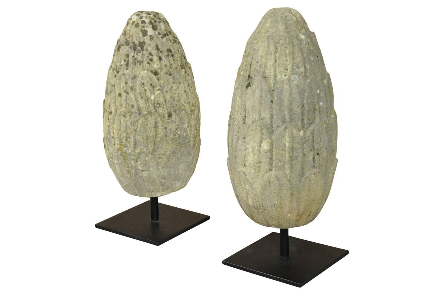 A sensational pair of mid-18th century carved stone finials, pineapples from France. These wonderful architectural elements are presented on iron stands. Terrific accent pieces for a mantel, table top or converted into lamps.