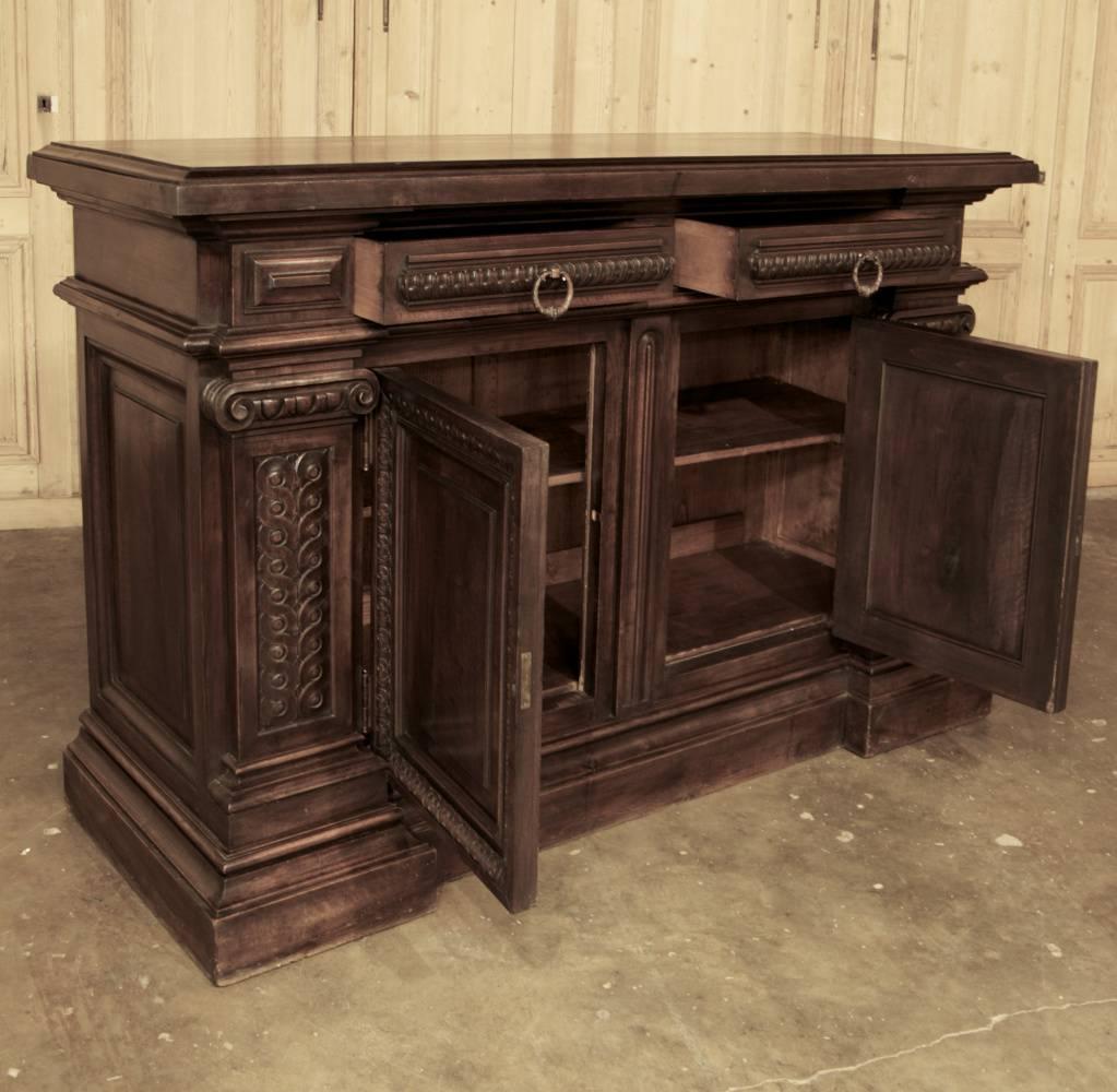 Handcrafted from solid Italian walnut in the Romanesque interpretation of the Classical style, this handsome 19th century Italian walnut buffet will present an imposing presence in any room! Double rows of Greek coins form the pilasters topped with