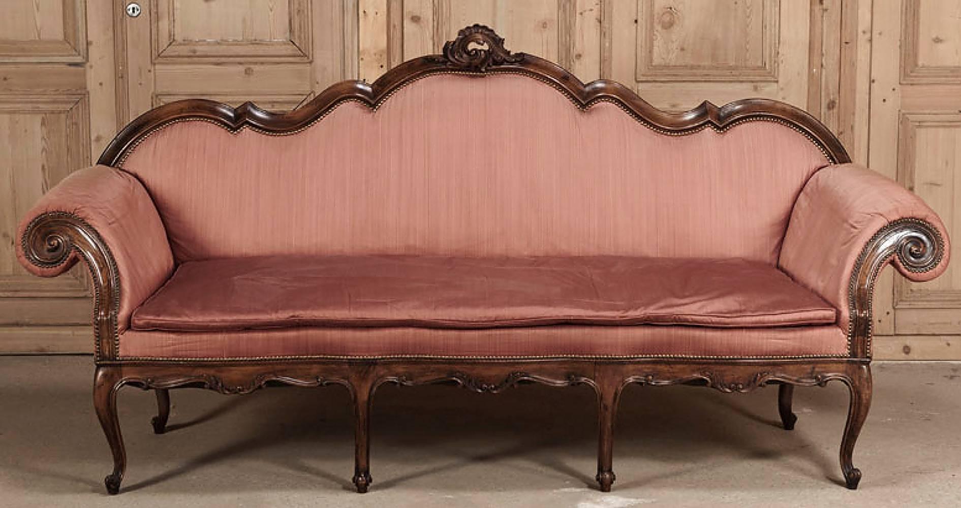 Clearly illustrating the opulence of the Italian Baroque style, this grand antique Italian Baroque walnut sofa was sculpted with elegant lines from fine walnut then completed with serviceable silk upholstery. 
circa 1870s. 
Measures: 45 x 94 x 28;