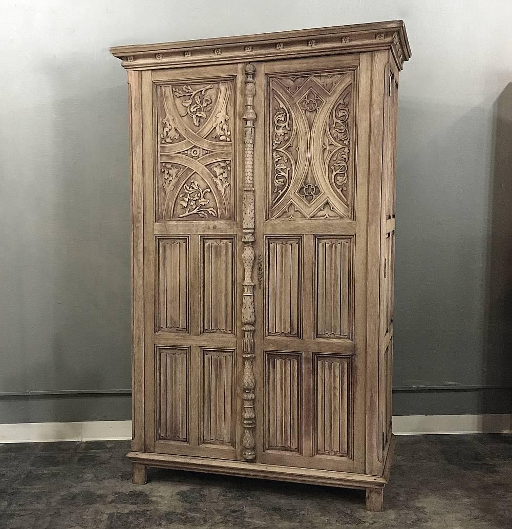Antique Flemish Gothic Revival washed stripped oak armoire represents the epitome of the style, with stylized geometric carvings combined with linen fold panels. Carved on all three sides, it boasts an astragal that covers the natural gap between