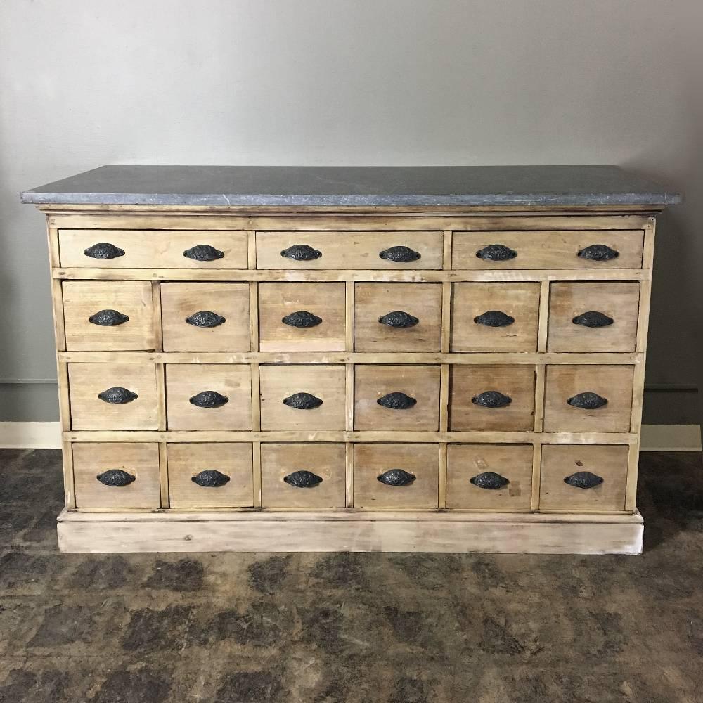 Rare find. This well preserved antique marble-top pharmacy counter features a thick dark gray marble-top and a cabinet below that on one side boasts no less than two dozen drawers, all fitted with cast iron pulls. Ideal as a kitchen island or an