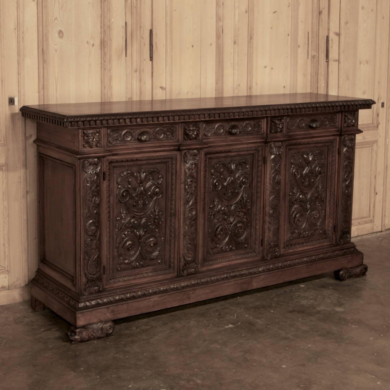 The splendor of the Renaissance style has been captured in fine Italian Walnut with this exceptional Hand-Carved Antique Buffet! Featuring elaborate relief carved into each of three large door panels surrounded by bold molding, carved drawer