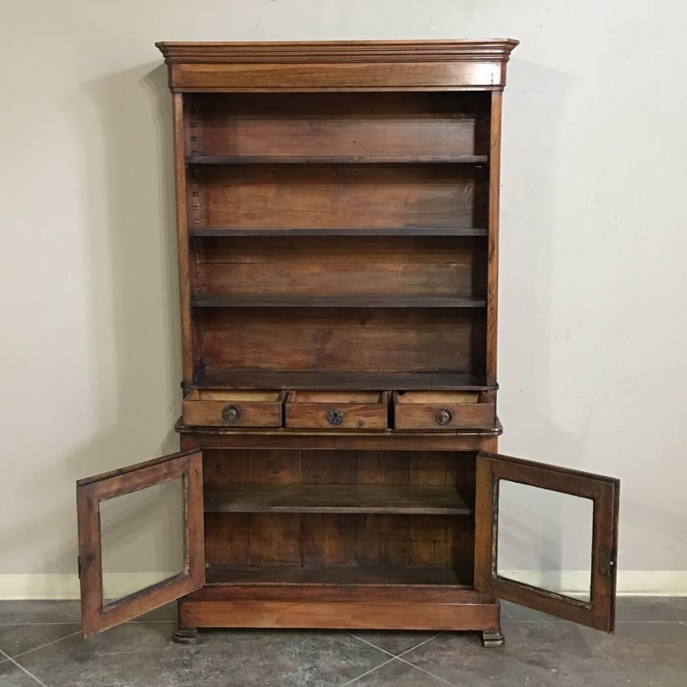 A rare find, this 19th century Louis Philippe Pharmacy bookcase will add a sense of rustic sophistication to an office or storage space. The open shelving, three small drawers and ample cabinet with glass doors offer charm and versatility. A