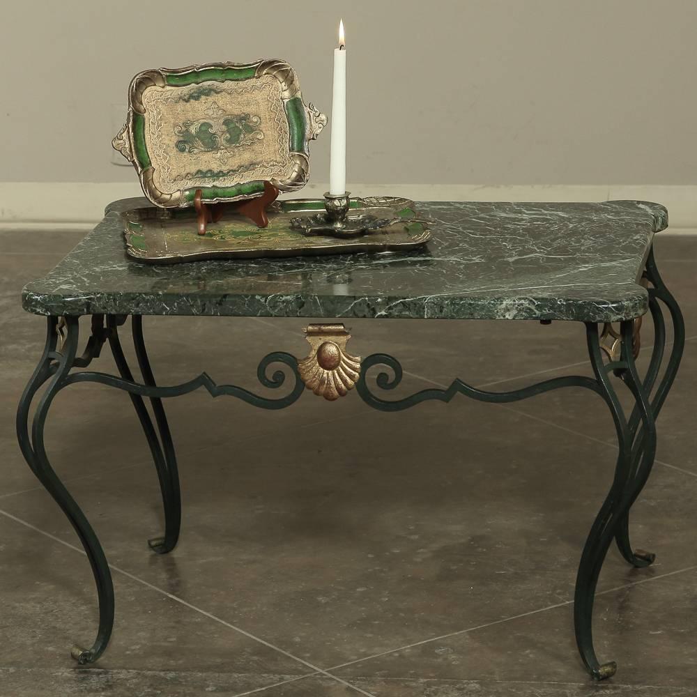 Art Deco French wrought iron marble-top coffee table displays the talents of the hard-working metalsmith who painstakingly forged the iron into the graceful shapes and scrollworks that comprise the frame and legs for this work. A shell highlighted