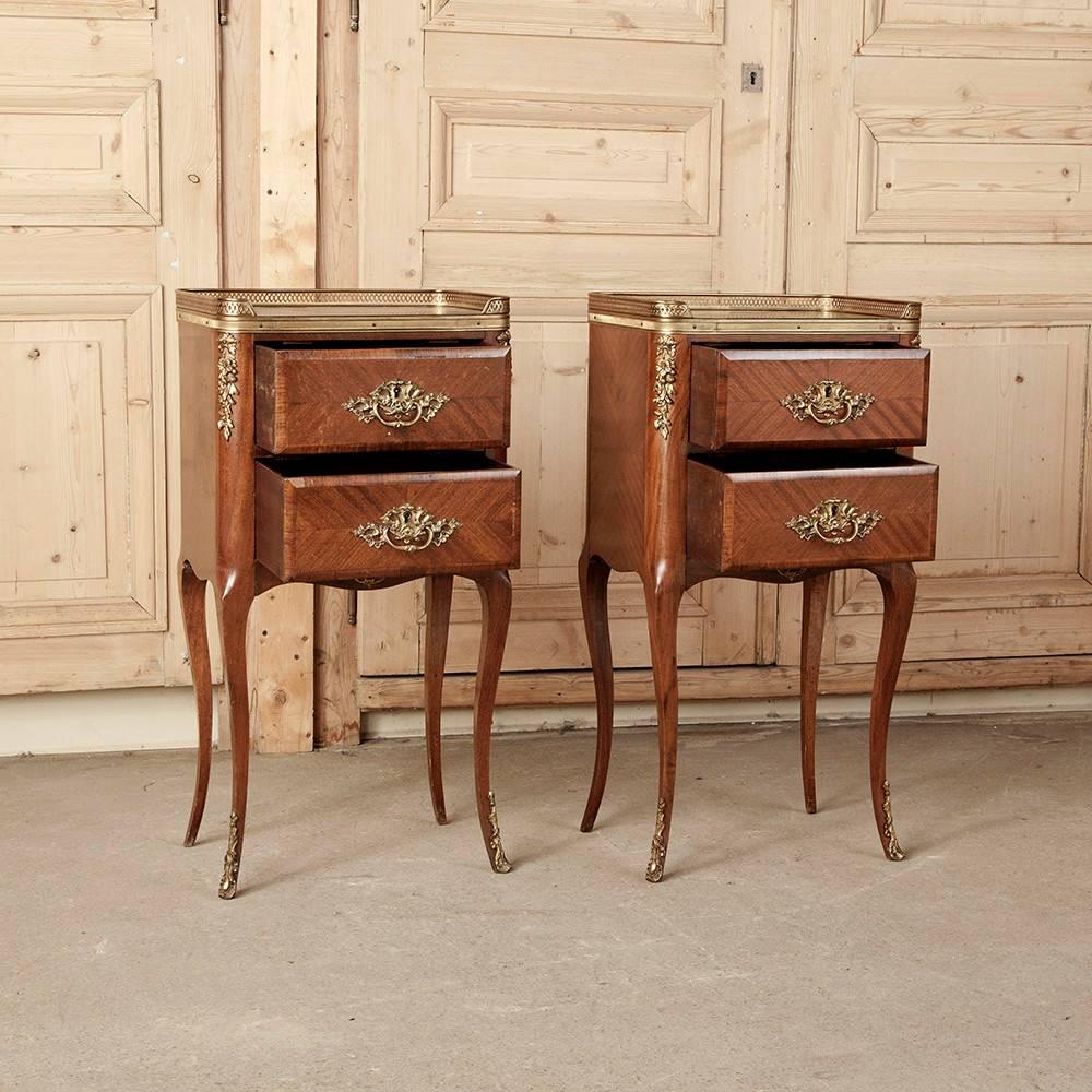 This pair of French marquetry nightstands were crafted with mahogany and inlaid with fine woods such as satinwood, heart walnut and boxwood for contrast, creating artistic patterns in the wood, which we call marquetry. This pair even features cast