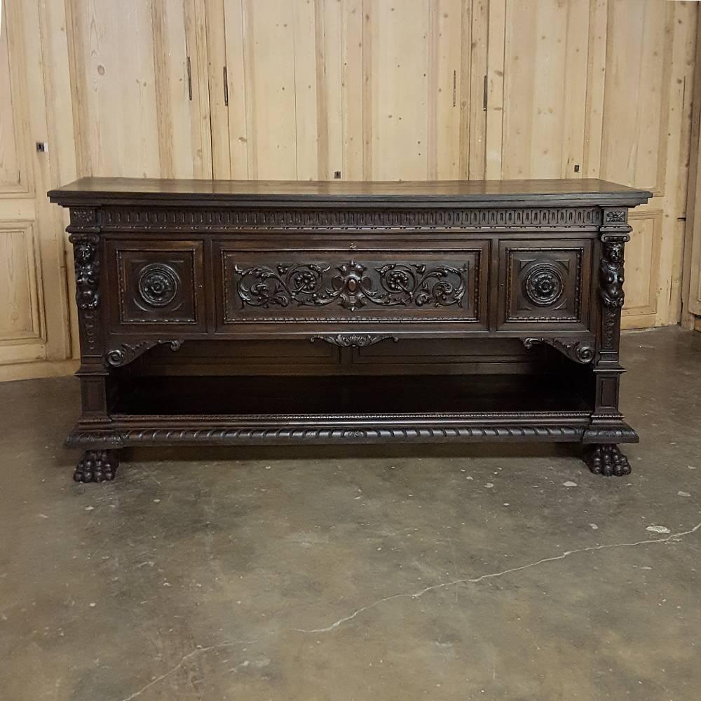 Sculpted from fine walnut, this impressive antique Italian Renaissance Buffet with lion's paw feet is the perfect choice for the masculine decor! Caryatids on each corner atop pilasters flank the three carved panels across the facade, each decorated