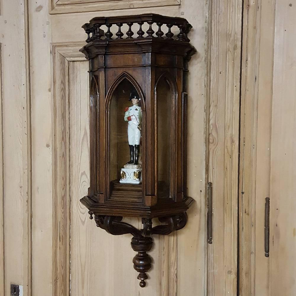 19th century French Gothic wall vitrine or curio cabinet with sconce makes the perfect display case for wall-mounting a small to medium-sized statue. Incredibly detailed casework sculpted from solid walnut features multi-faceted sides glazed with