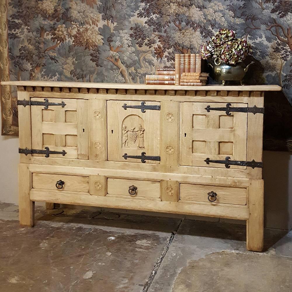 Fitted with oversize hand-forged iron strap hinges, this impressive antique rustic Gothic Buffet stretches almost eight feet in width, and is perfect for a large wall in an office or home where a surface for display and copious storage is required!