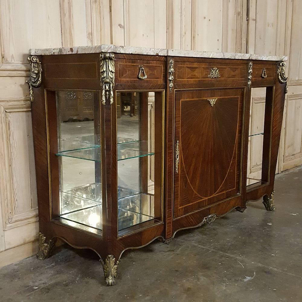 This exceptional 19th century French Louis XVI marble-top display buffet example boasts its original beveled marble-top, exotic inlaid mahogany, bronze ormolu mounts, and rounded, mirrored display shelves ~ all in original condition expertly
