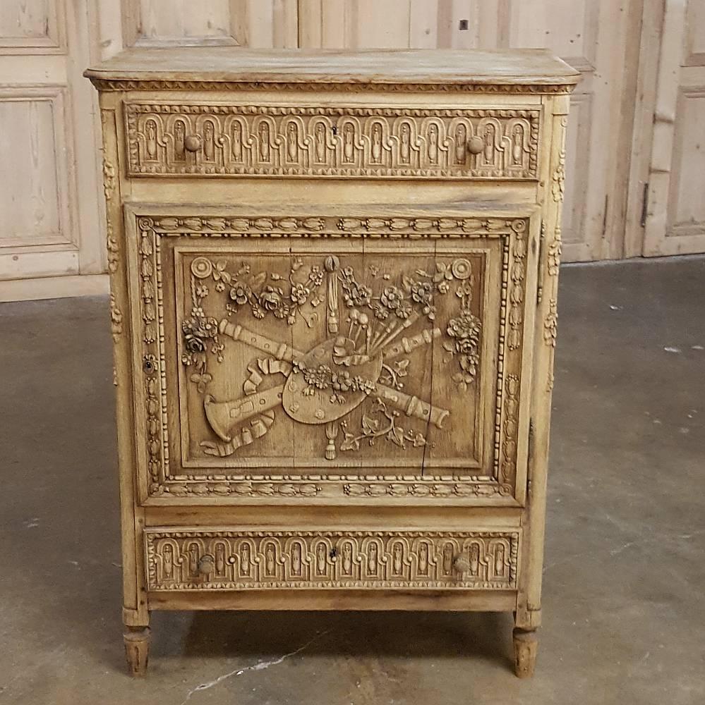 Early 19th century Country French hand carved stripped oak neoclassical Louis XVI confiturier is perfect for cozy niches and has been carved with floral and foliate designs as well as musical and artistic motifs. Stripped finish makes it perfect for