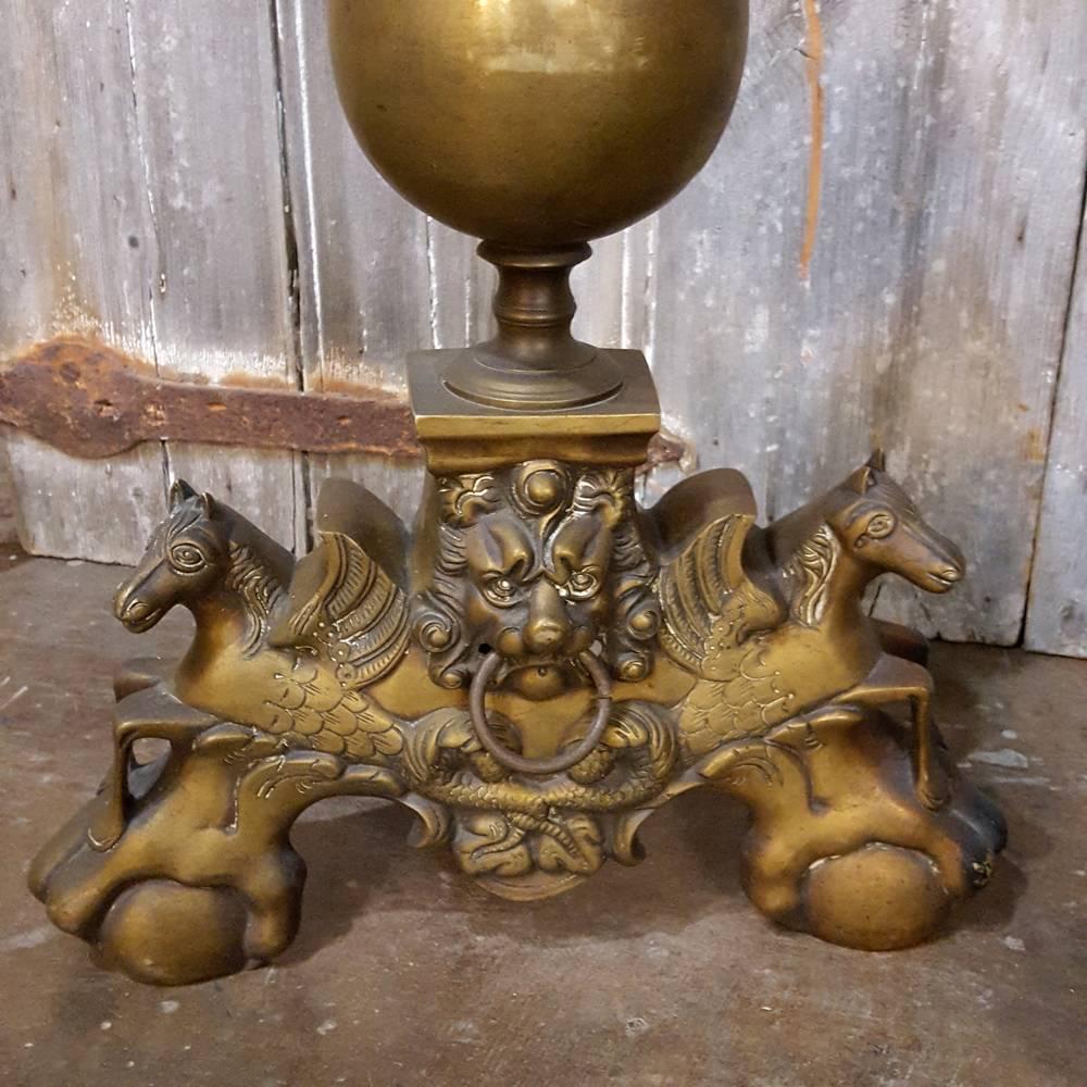 This pair of impressive and grand 19th century bronze French Baroque andirons feature lions' heads and with Pegasus Winged Horses as the main design motif, with talon and ball feet, and two orbs above finished with a flame finial. Perfect for