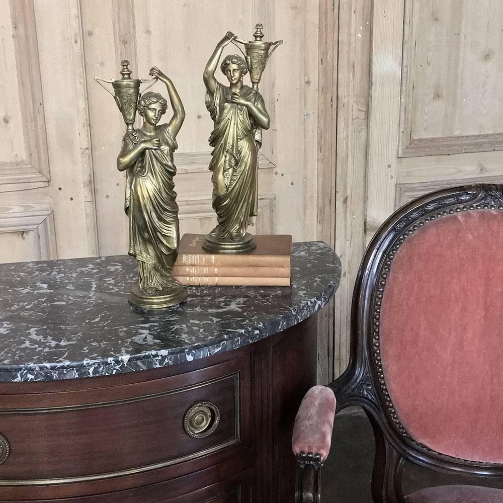 This lovely pair of 19th century bronze Louis XVI statues depict caryatids, which first appeared in the classical form in ancient Greek architecture. Styled to imaginatively reflect young maidens carrying water jugs, the motif has been used for