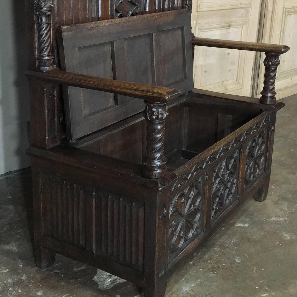As 19th century French Gothic hall benches go, this is an unusual example! Measuring over six feet ten inches high, it is barely three feet wide! Spectacularly sculpted from the spires to the pierced crown to the seatback panels and the trunk base