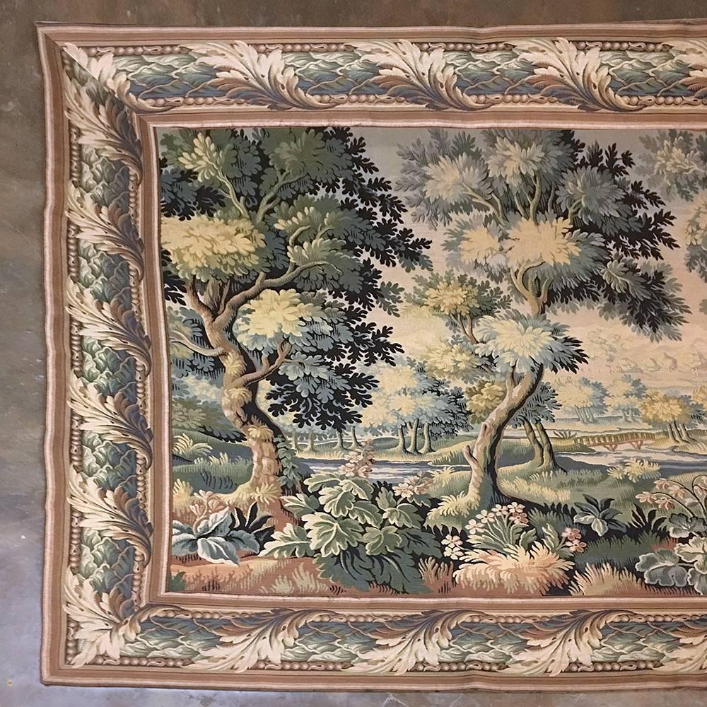 This Antique Belgian Renaissance tapestry was woven from wool on a grand scale, and depicts a stunning and vibrant pastoral scene with an abundance of green colors predominating the work. Measuring almost eight feet tall and over 16 feet wide, it is