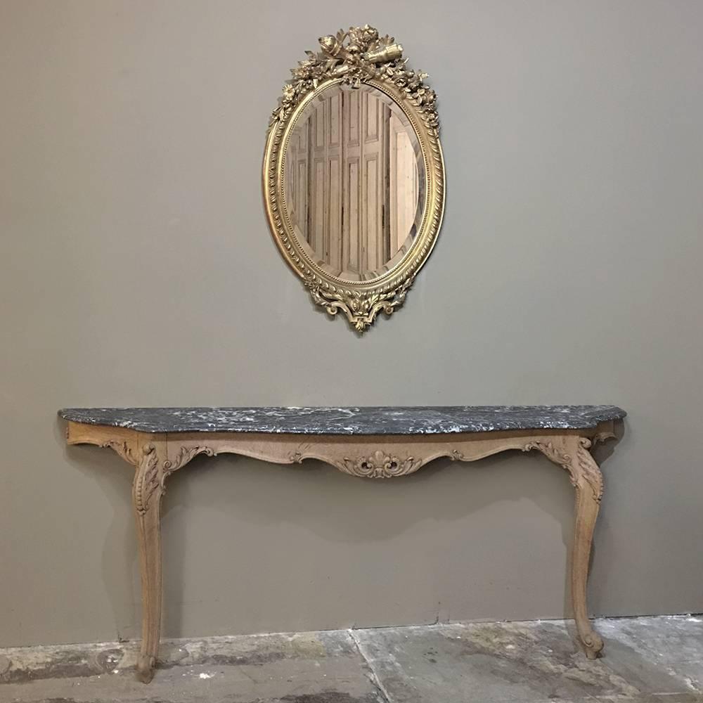 19th century French Louis XVI oval gilded mirror is a masterwork of timeless style! The egg and dart variation on the framework is lavished with sprays of floral and foliates cascading down from the centrepiece at the top which is a Carquois de