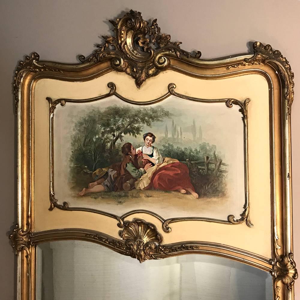 19th century French Louis XV giltwood Trumeau features a lovely patinaed painted finish that has been highlighted in gold, all decorating a superbly crafted Rococo style trumeau that combines a romantic oil painting of a courtship between two rural