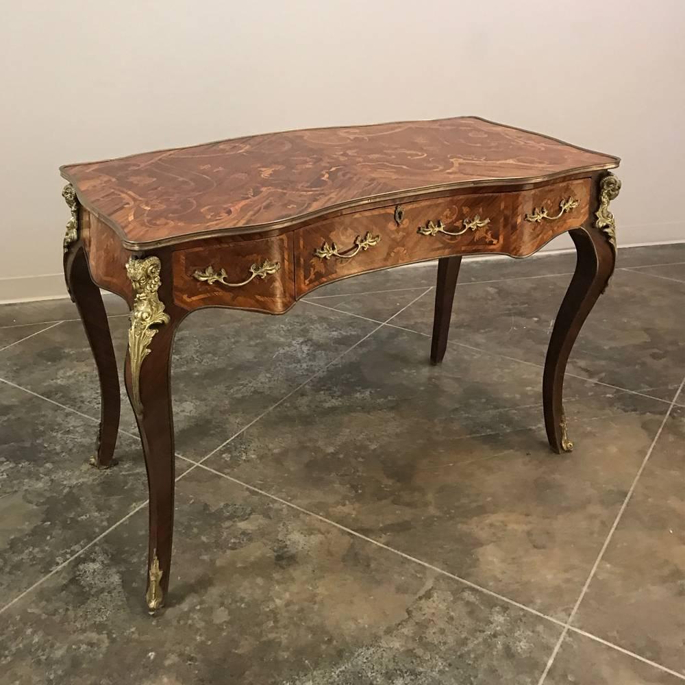 19th century French Louis XIV marquetry desk features exotic wood veneering all around accented by inlay work and marquetry which is artistry using inlay itself, plus the intricate contours of the Baroque style enhanced by bronzes mounts for the